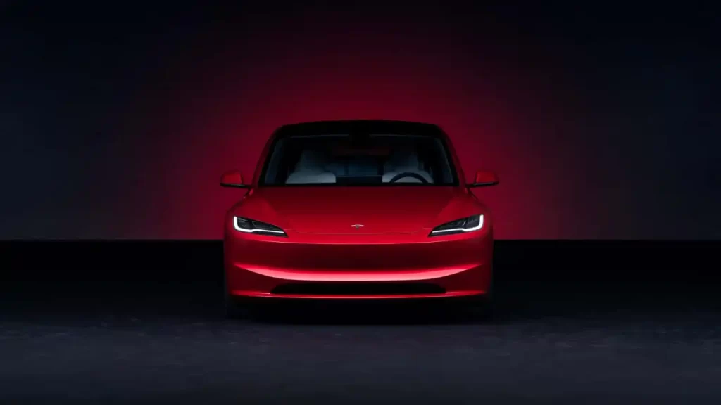 The red Tesla Model X is shown in a dark room at Tesla's Model 3 unveiling event.