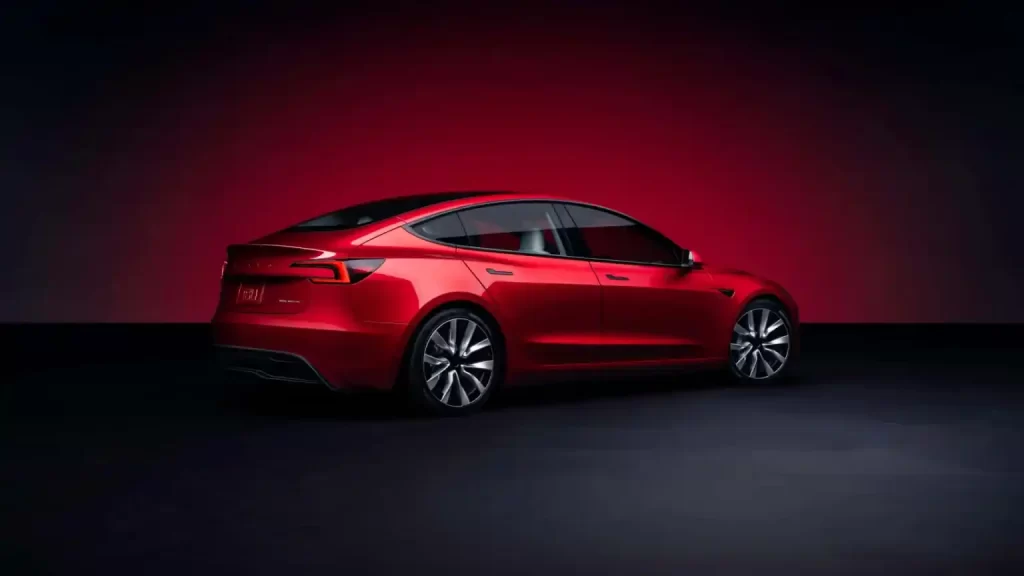 A red Tesla Model 3 with design tweaks and enhanced range in front of a red background.
