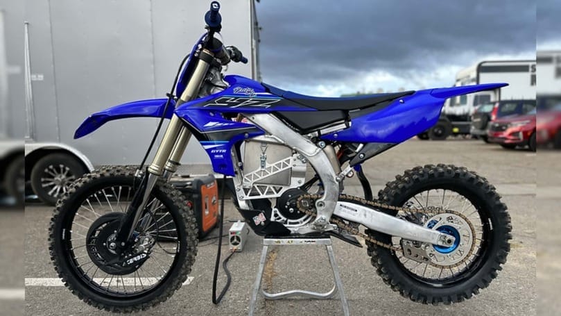 A blue dirt bike sitting on a stand.
