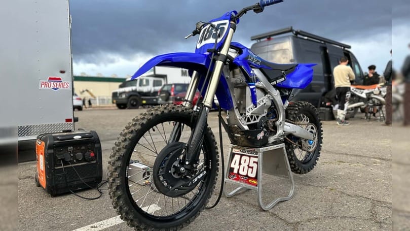 A blue dirt bike is parked in a parking lot.