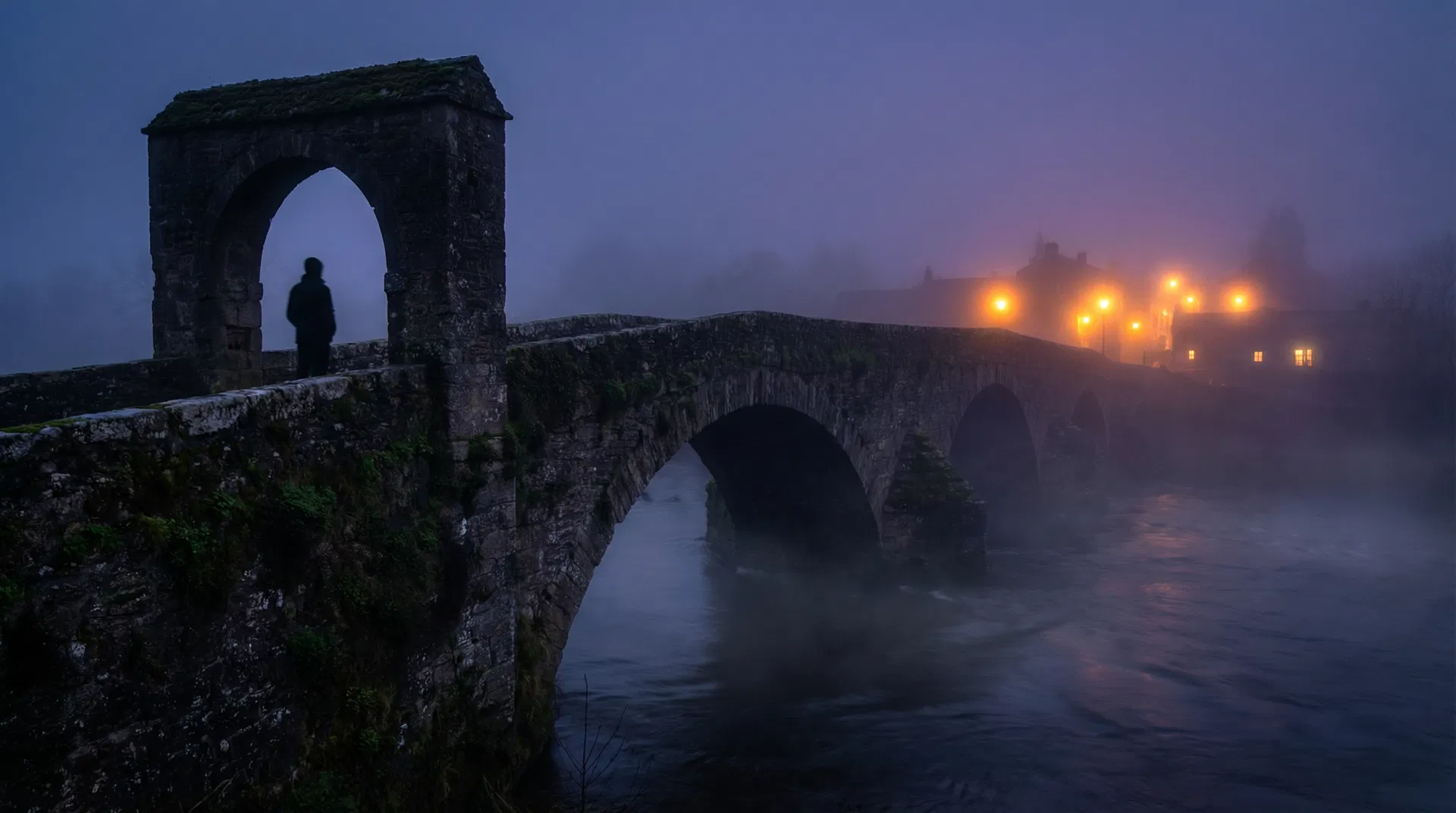 A silhouette standing at the entrance of a stone bridge at twilight, warm light ahead