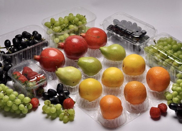 A gallery of thermoformed PET fresh produce packaging, including clamshells and punnets filled with various fruits and vegetables.