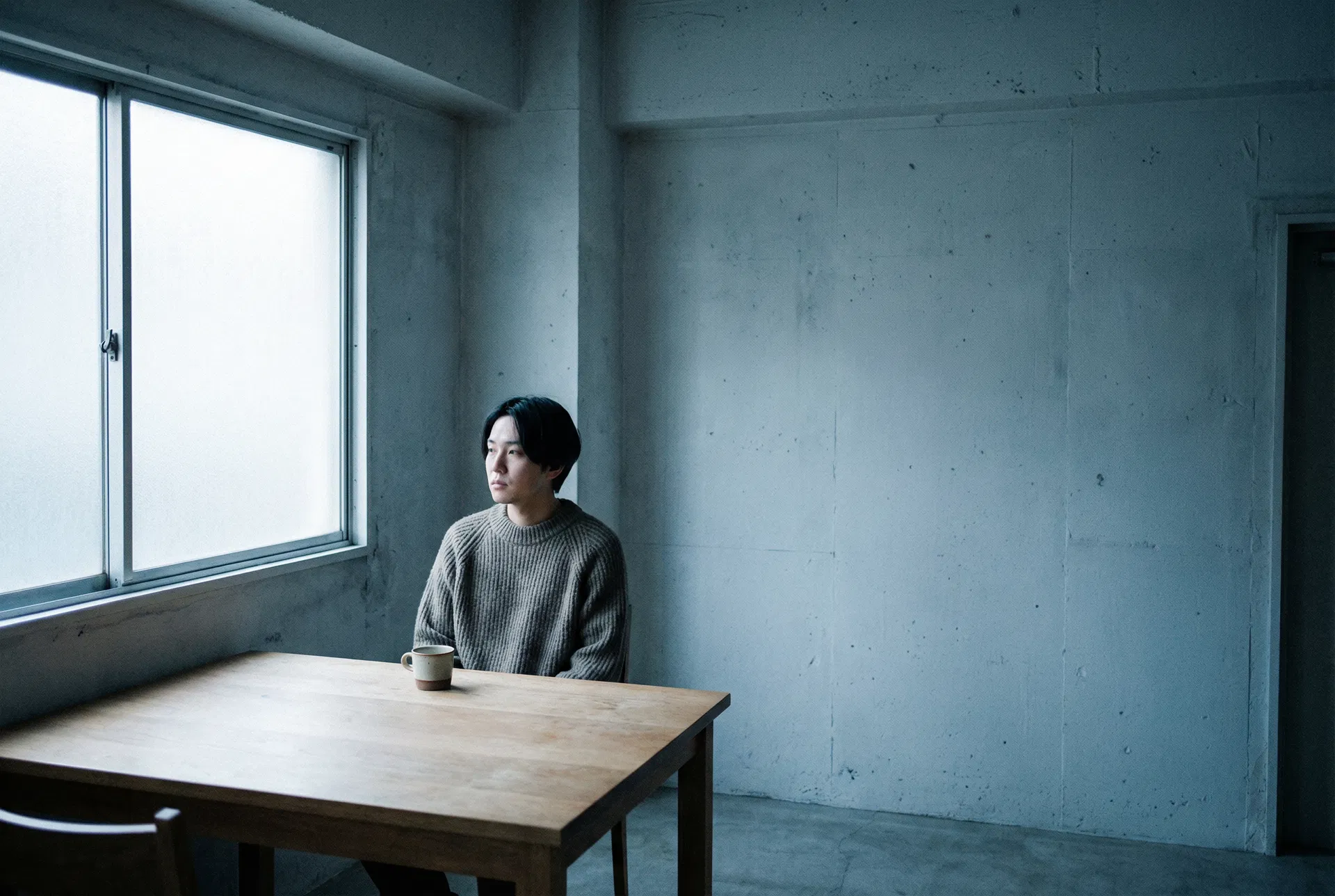 Persona sola a un tavolo minimalista — attaccamento evitante e autosufficienza come difesa