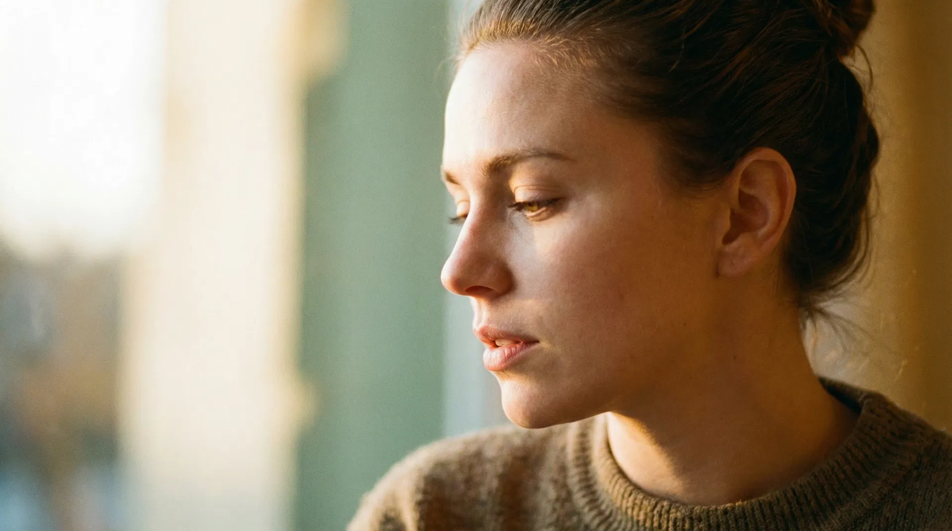 Donna di profilo con luce dorada laterale, espressione introspettiva e contenuta