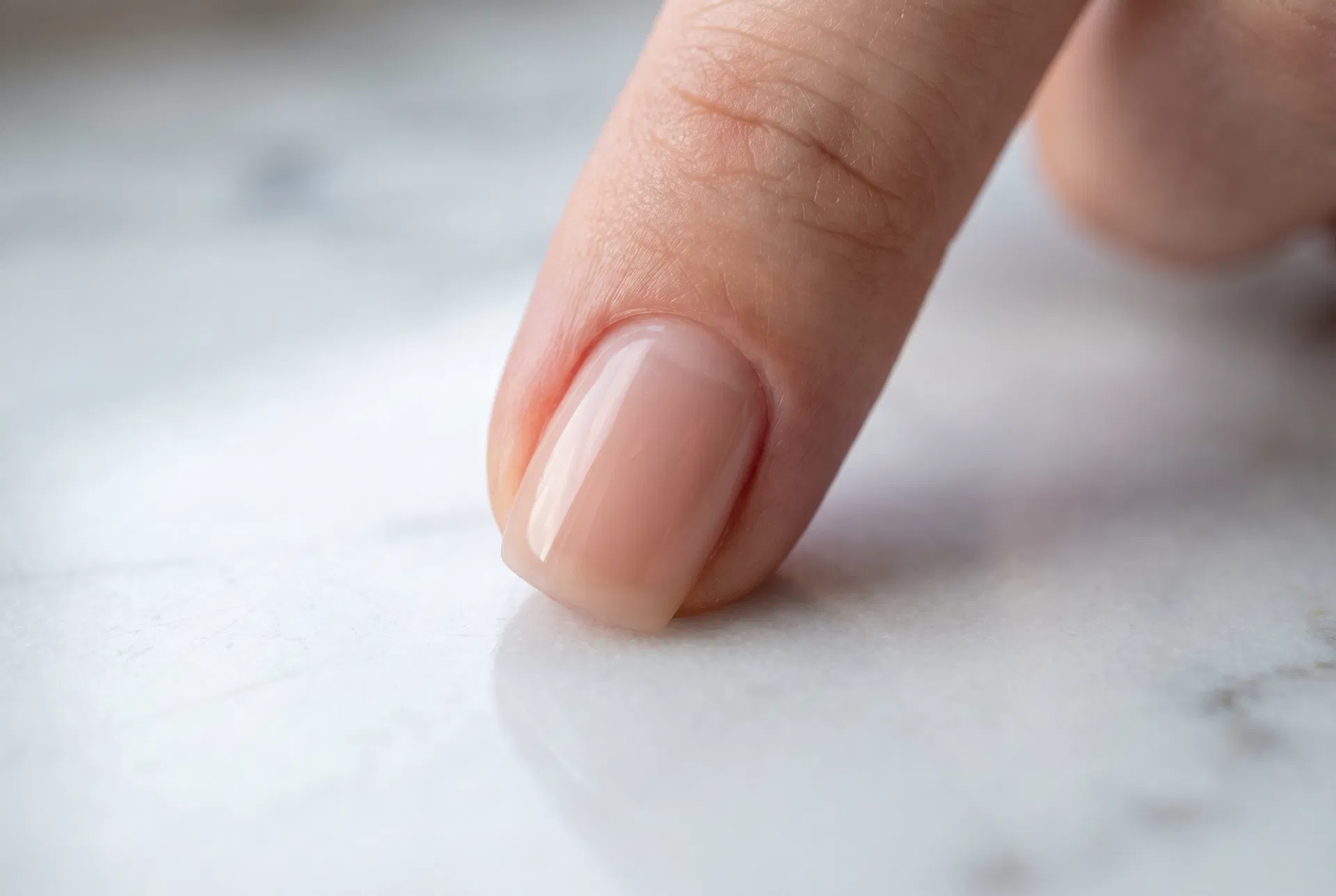 Extreme close-up of a fingernail showing the clean cuticle line result of a Russian Manicure