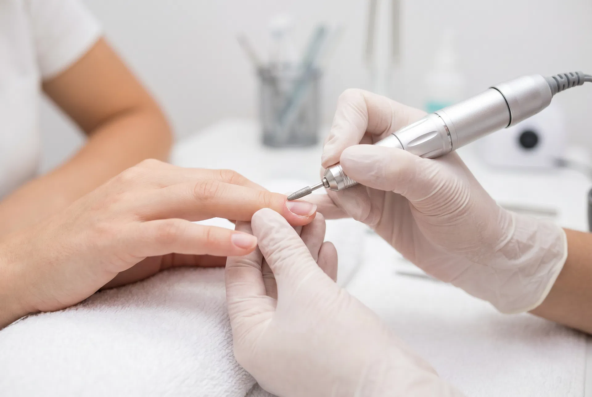 Nail technician using a precision e-file drill for Russian Manicure cuticle preparation