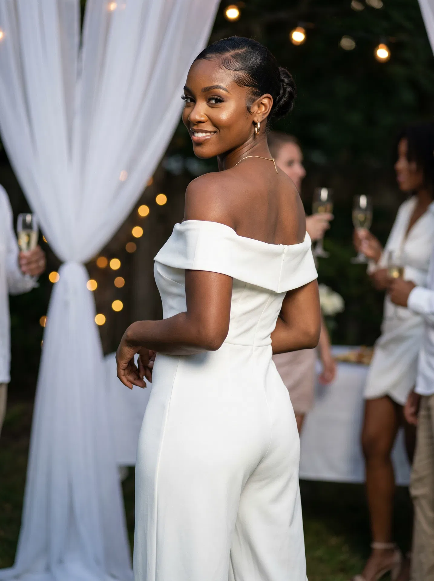 Woman in white off-shoulder jumpsuit at party
