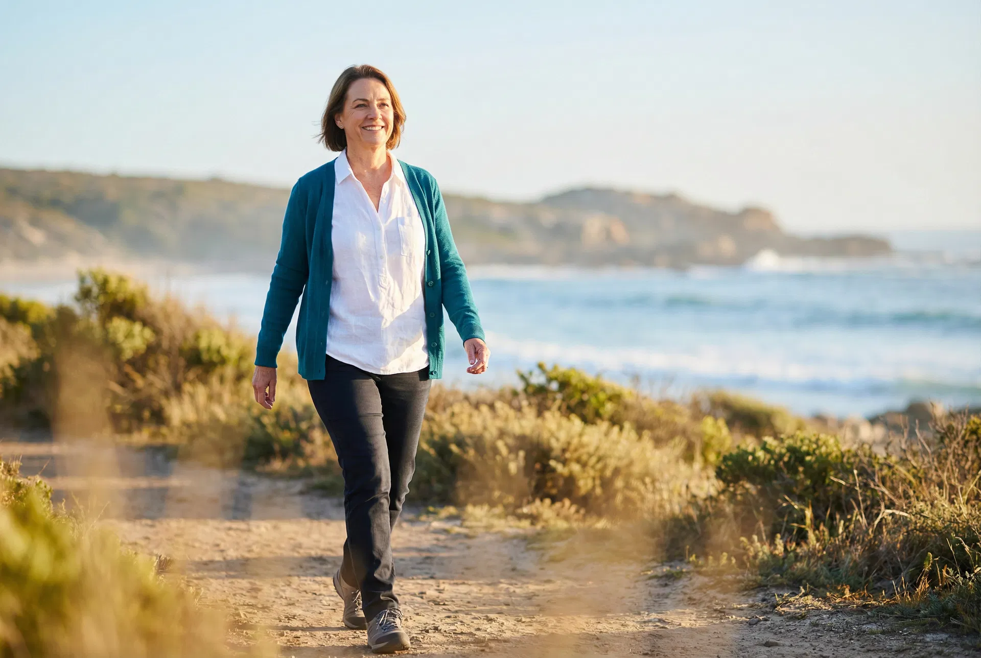 Woman walking on a coastal path, representing cognitive recovery and restored vitality
