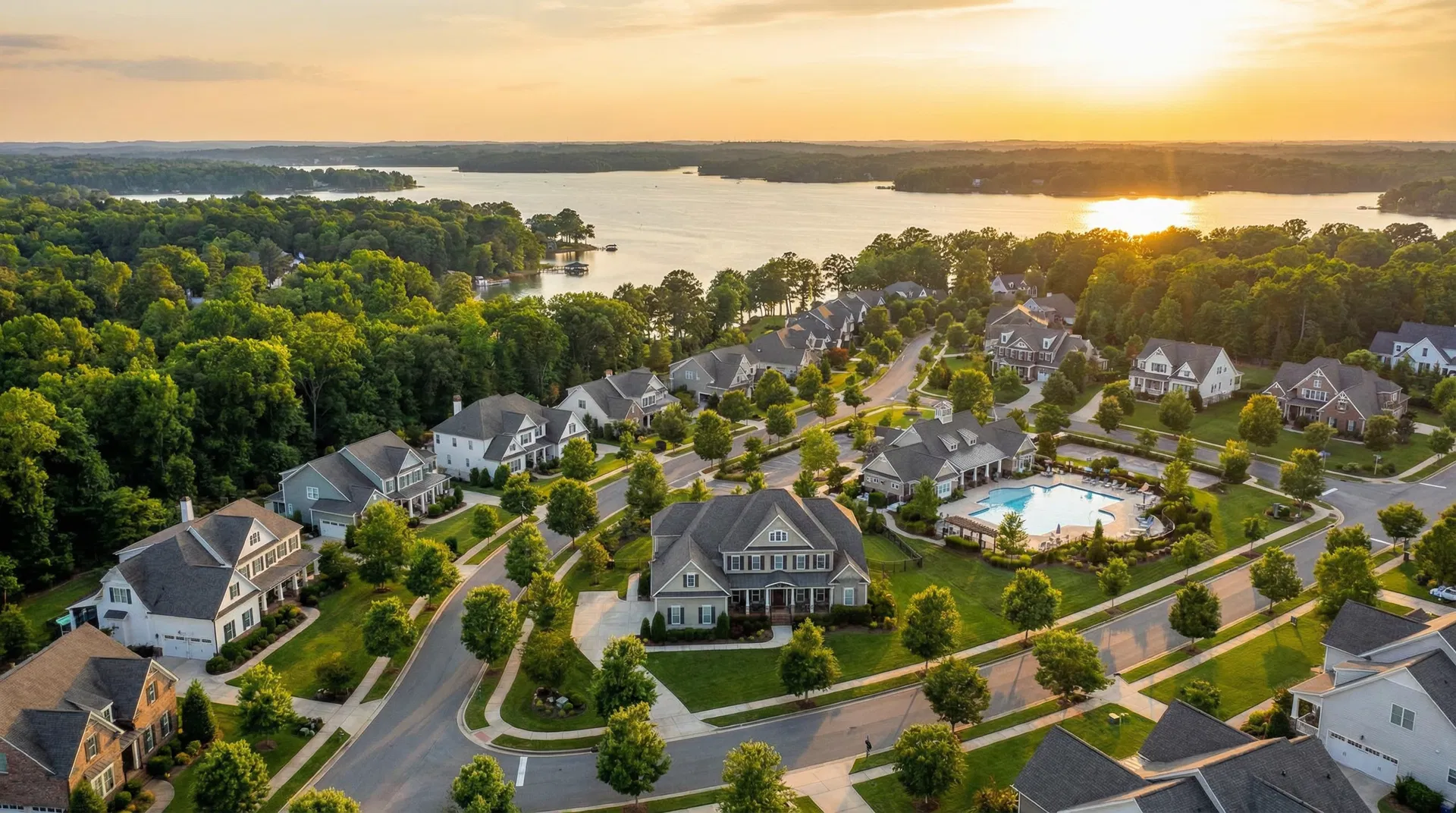 Aerial view of The Palisades community near Lake Wylie, Charlotte NC — luxury homes with tree-lined streets and community pool at golden hour
