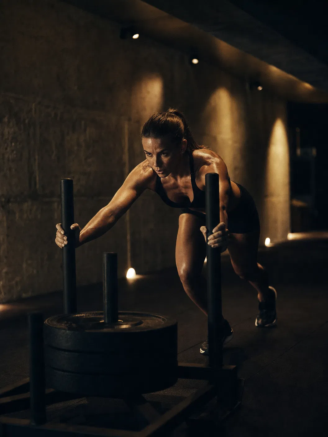 Female athlete performing sled push in private architectural training space