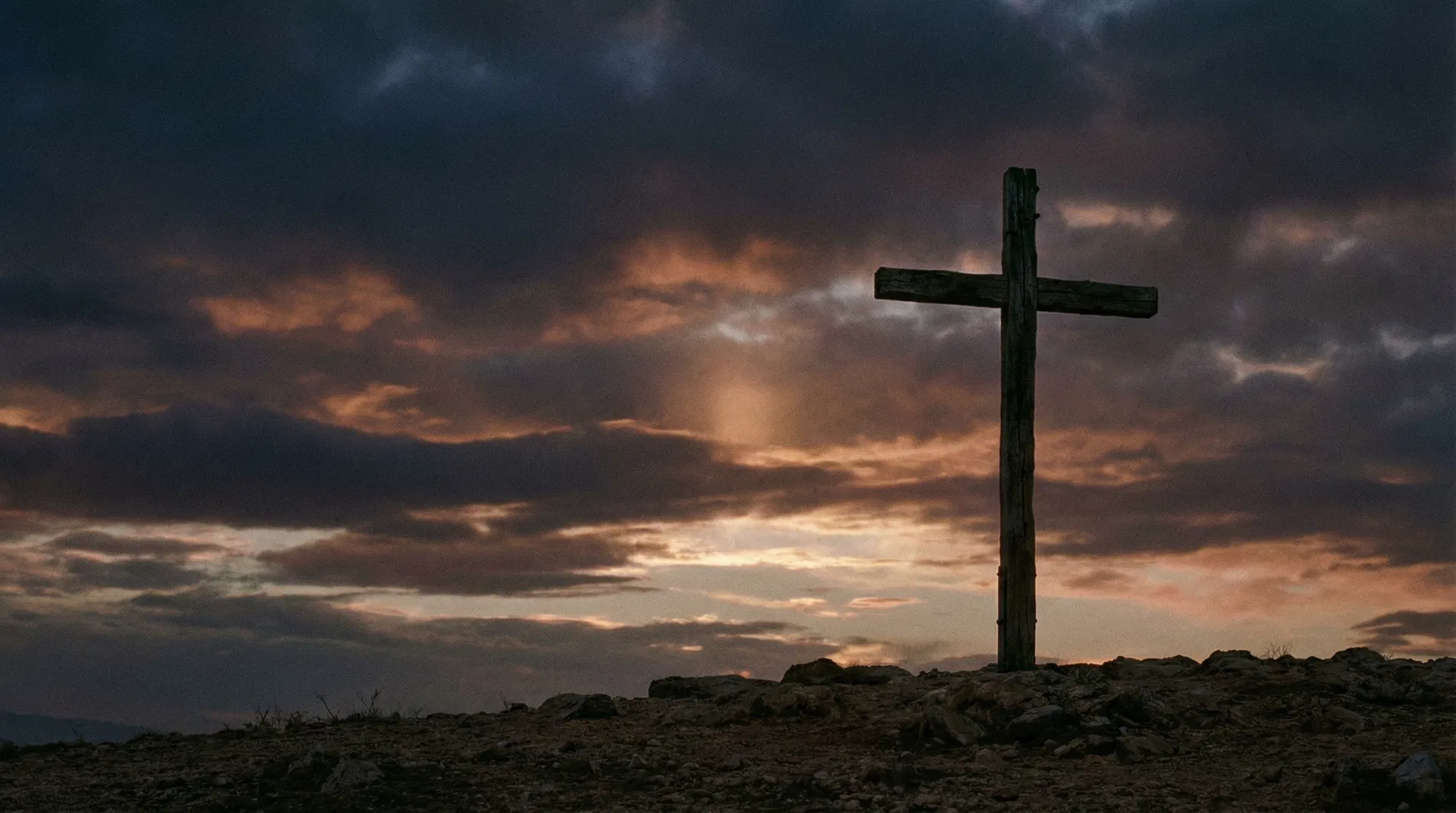 Cross silhouetted against dramatic sky