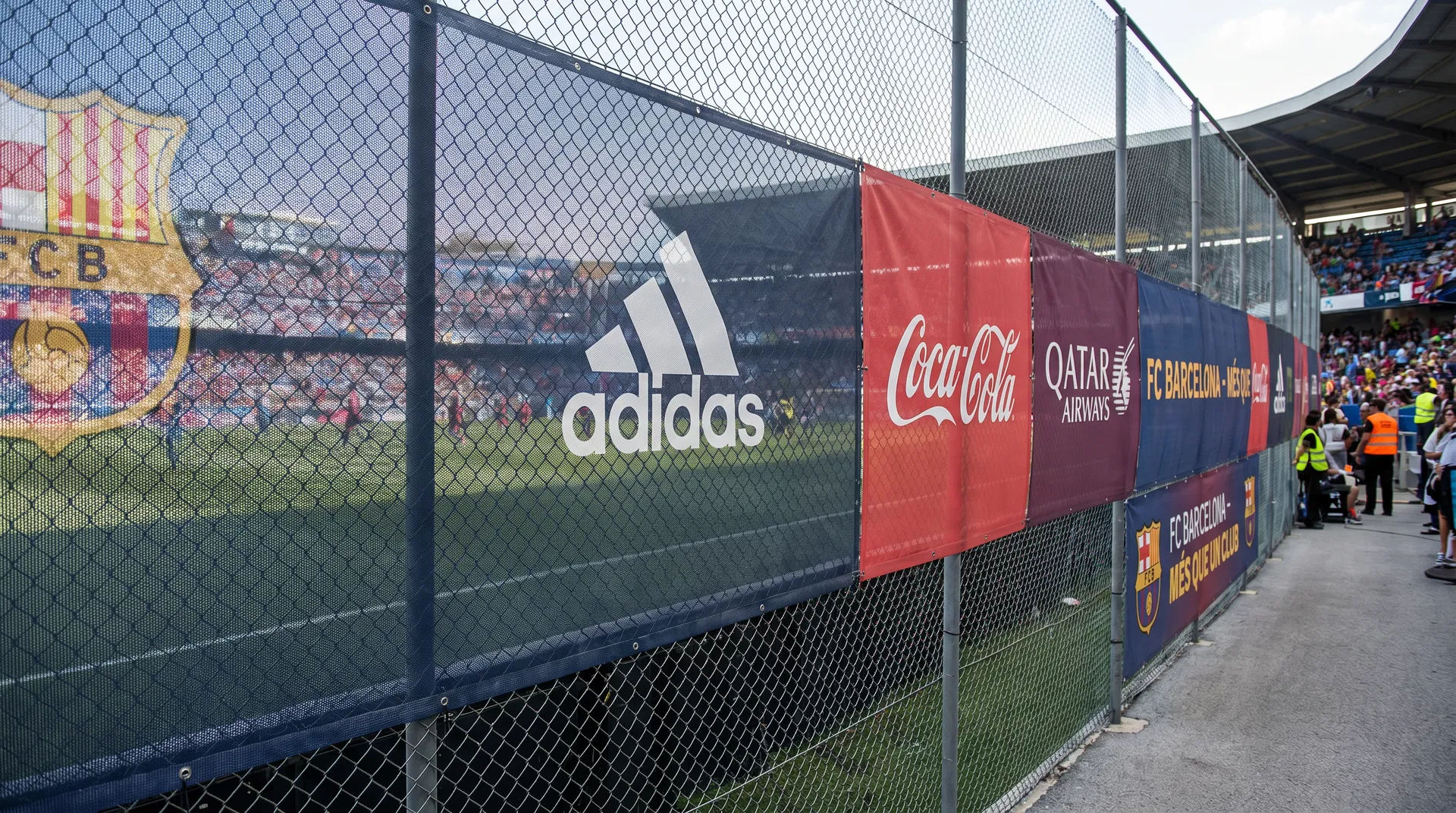 PVC mesh banners installed on sports stadium perimeter fencing with sponsor logos and team branding