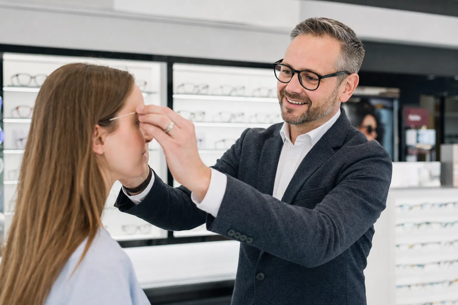 Augenoptiker passt Brille an Kundin an – modernes Optikergeschäft