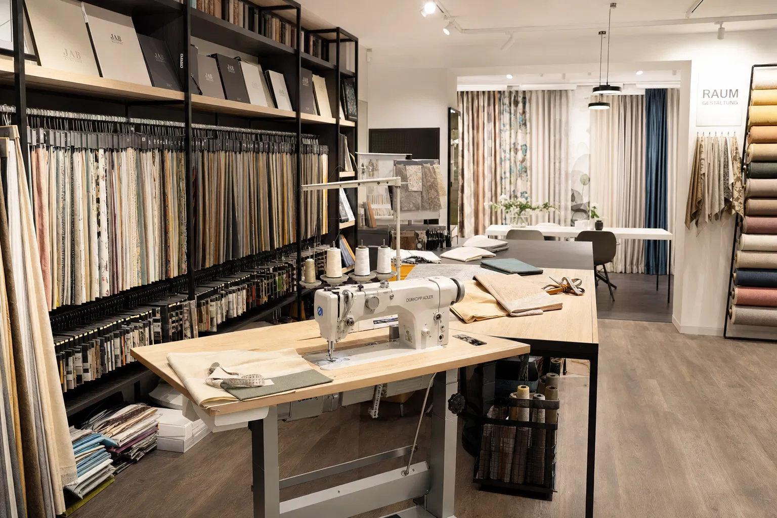 Professionelle Raumausstatter-Werkstatt mit Industrienähmaschine, Stoffrollen und Showroom