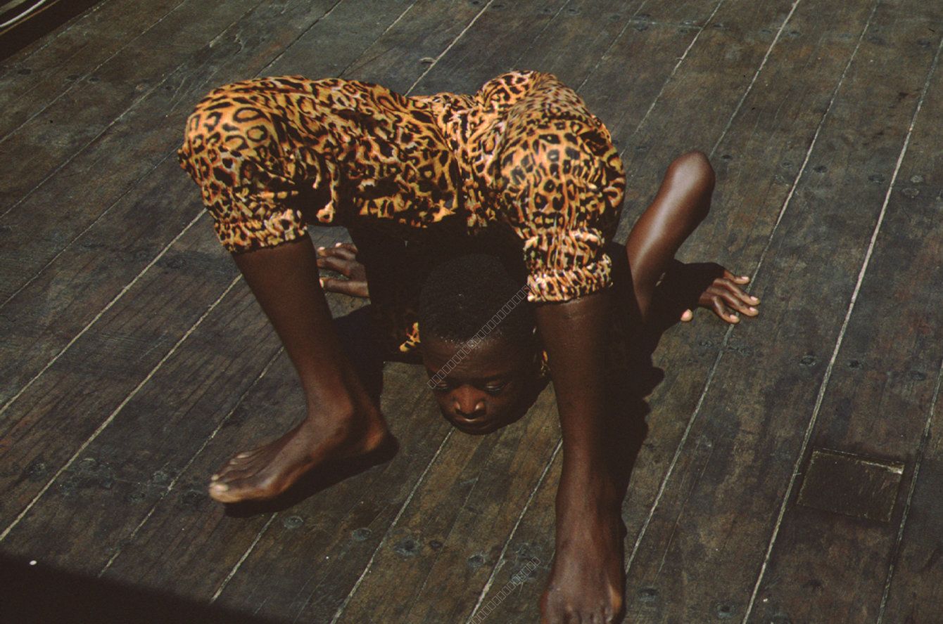 Acrobat in Leopard Print Trousers on Wooden Deck