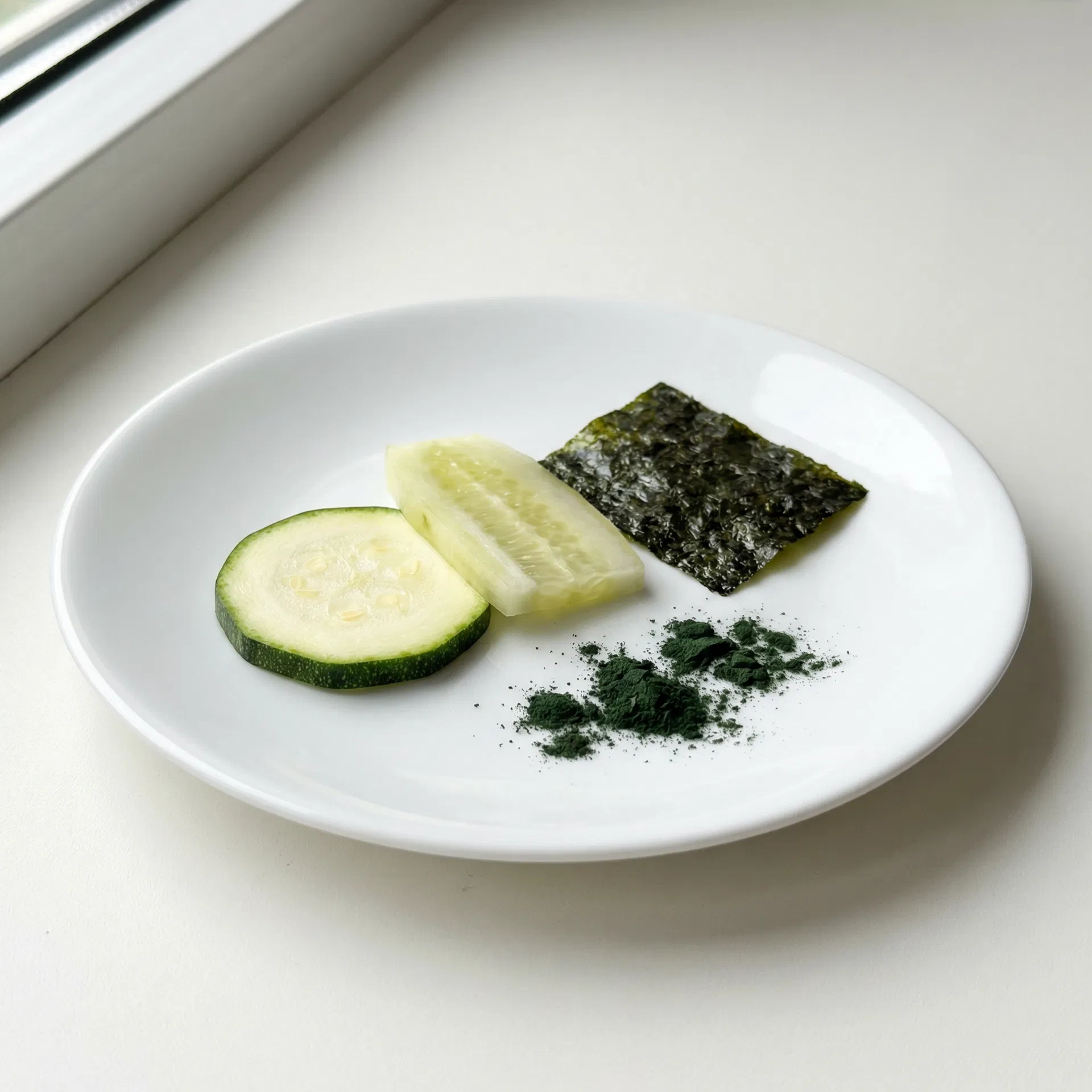 Zucchini-Scheibe, Nori-Algenblatt und Spirulina-Pulver als pflanzliches Fischfutter