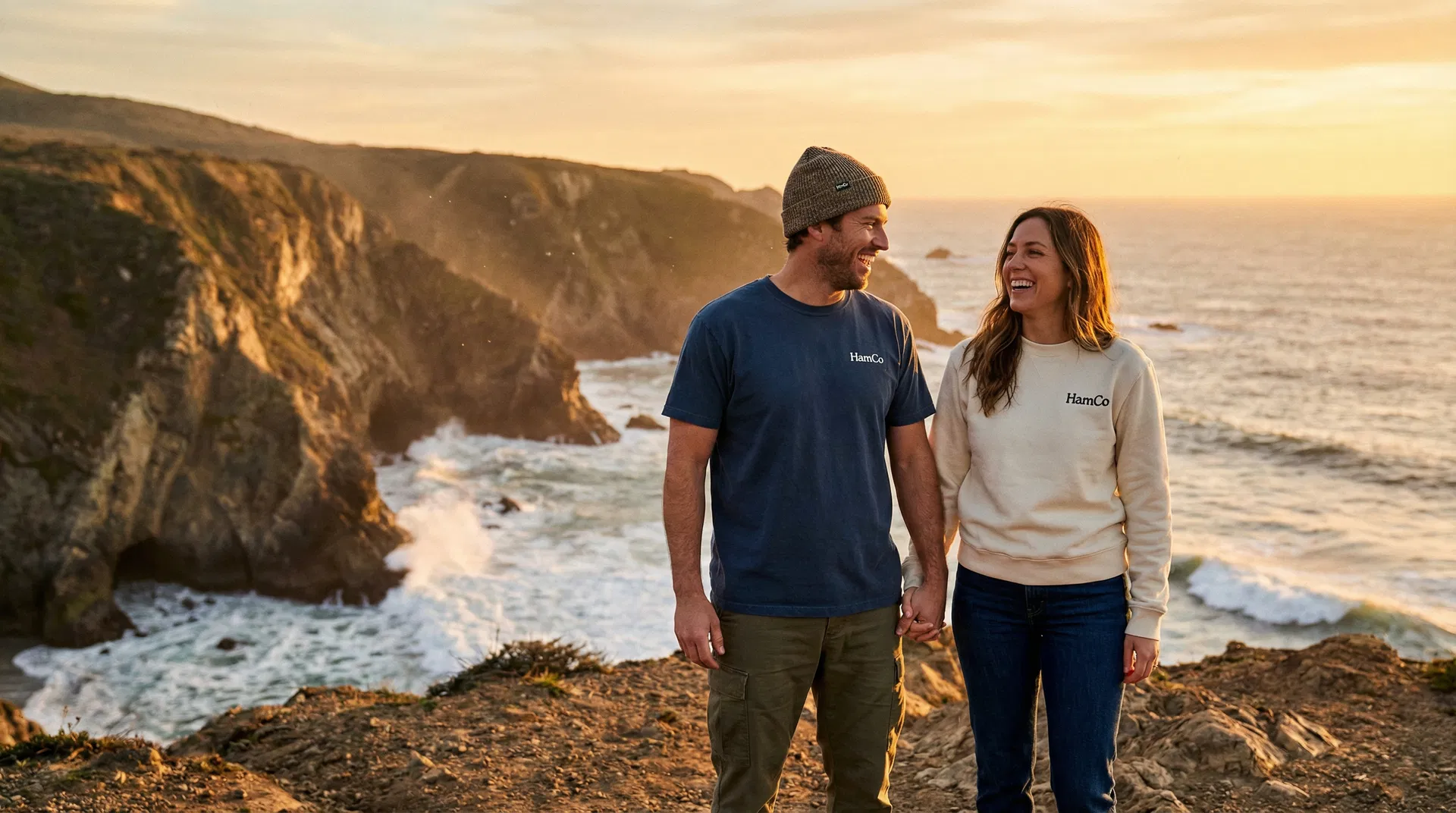 Couple wearing HamCo Supply apparel on a coastal bluff at golden hour