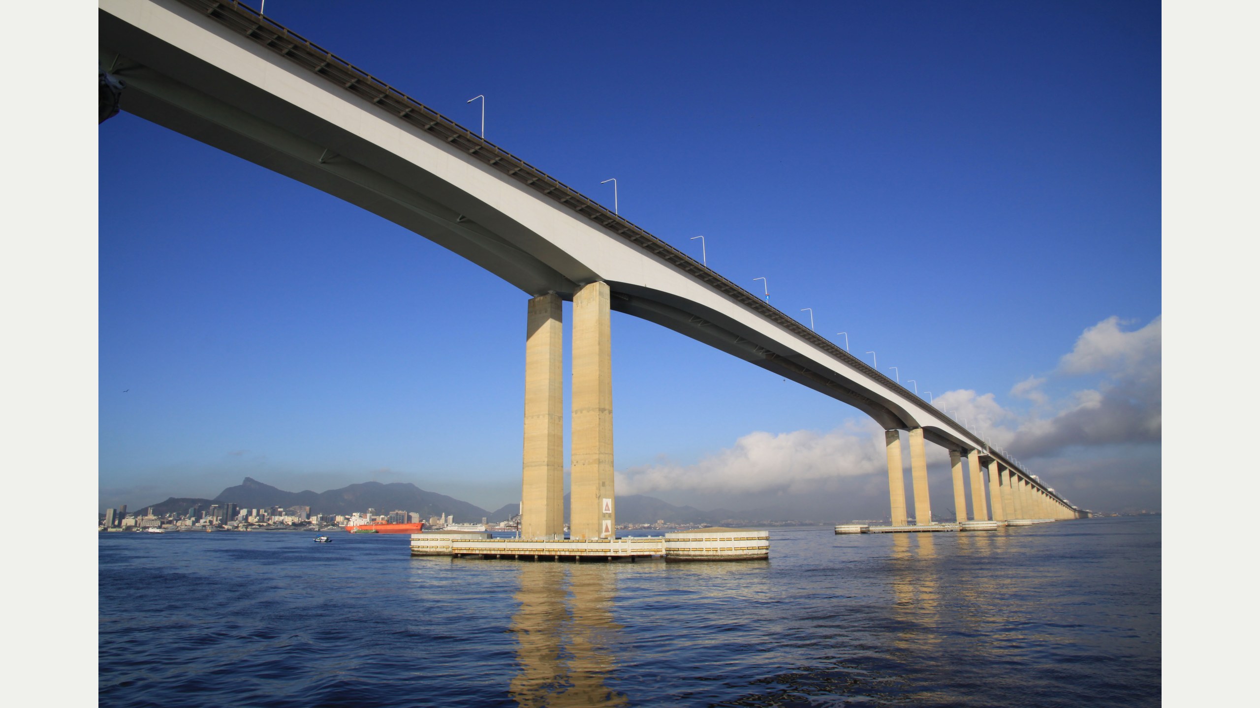 Vista lateral da Ponte Rio-Niterói sobre a Baía de Guanabara, com seus vãos de concreto e tráfego rodoviário ao fundo
