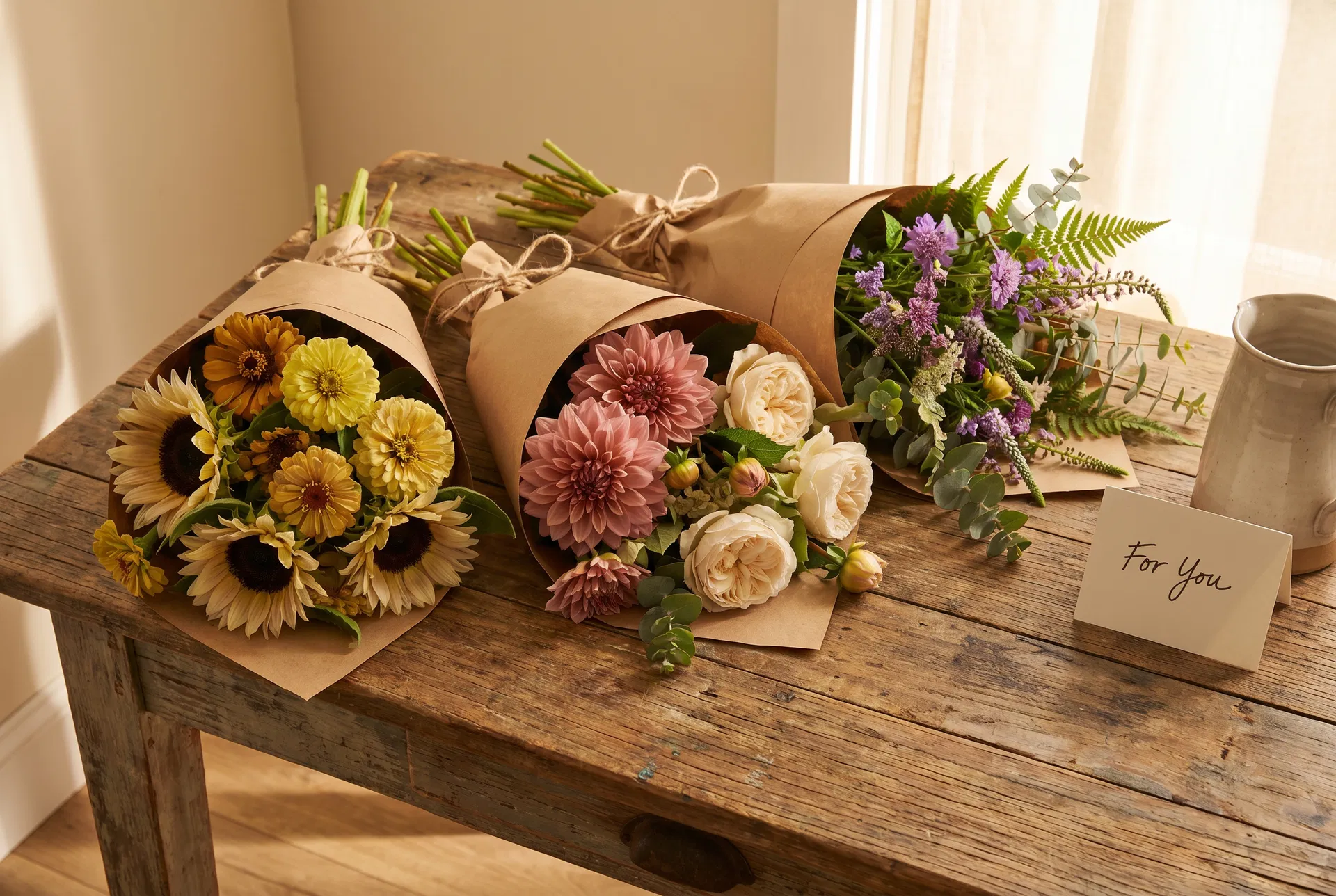 Three farm-fresh subscription bouquets wrapped in kraft paper