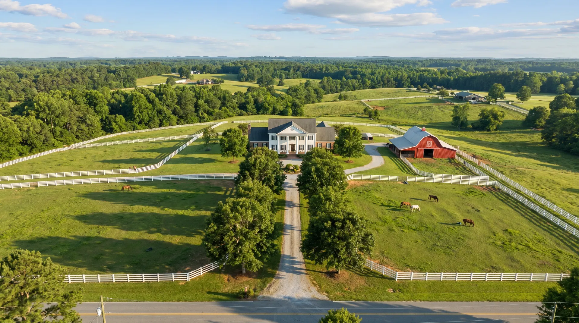 Aerial view of acreage horse property with white fencing, red barn, and Southern manor home in Fayette County, GA