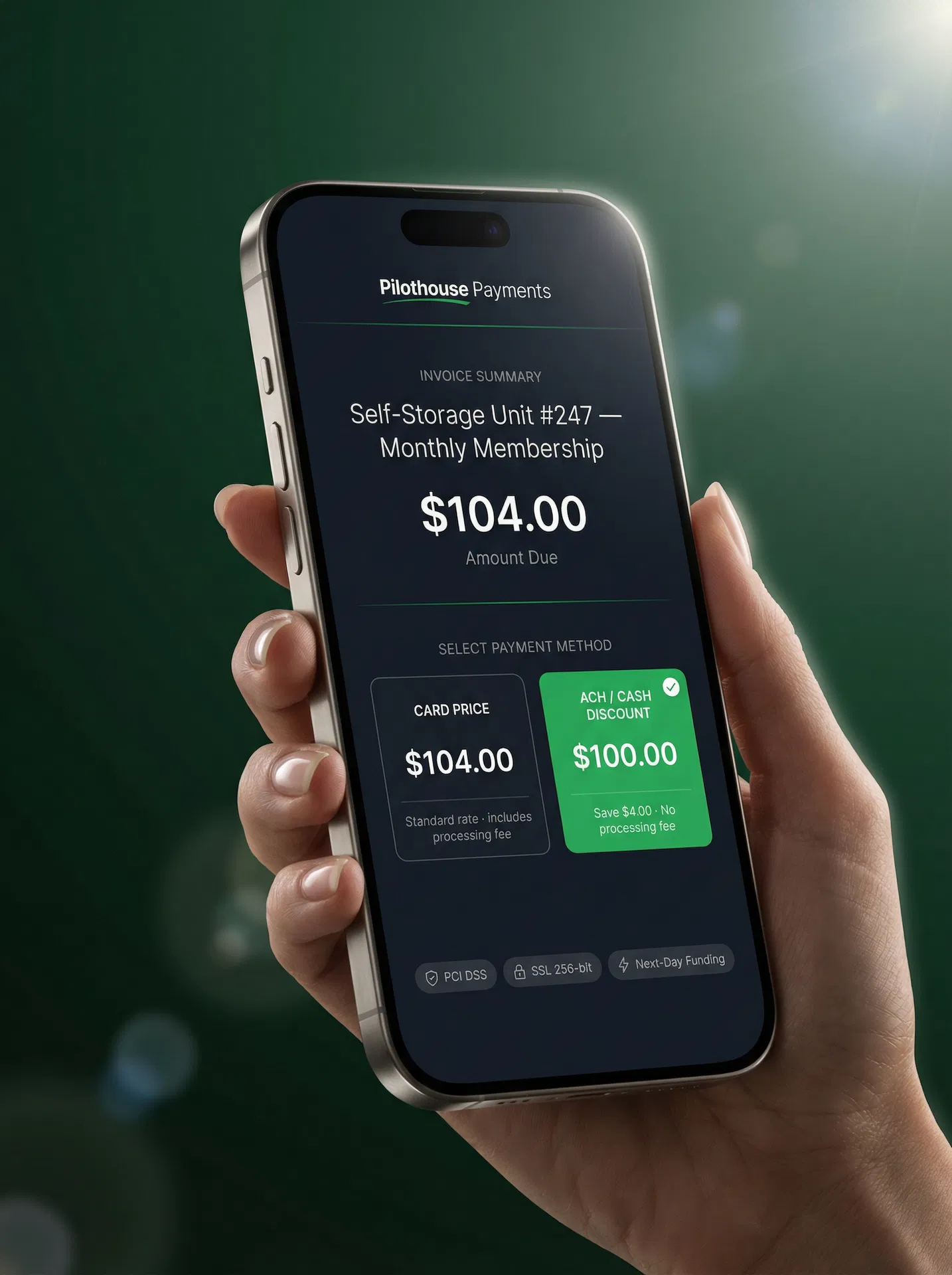 Hand holding a smartphone showing the Pilothouse Payments portal — Invoice $104.00, Card Price $104.00 vs ACH / Cash Discount Price $100.00