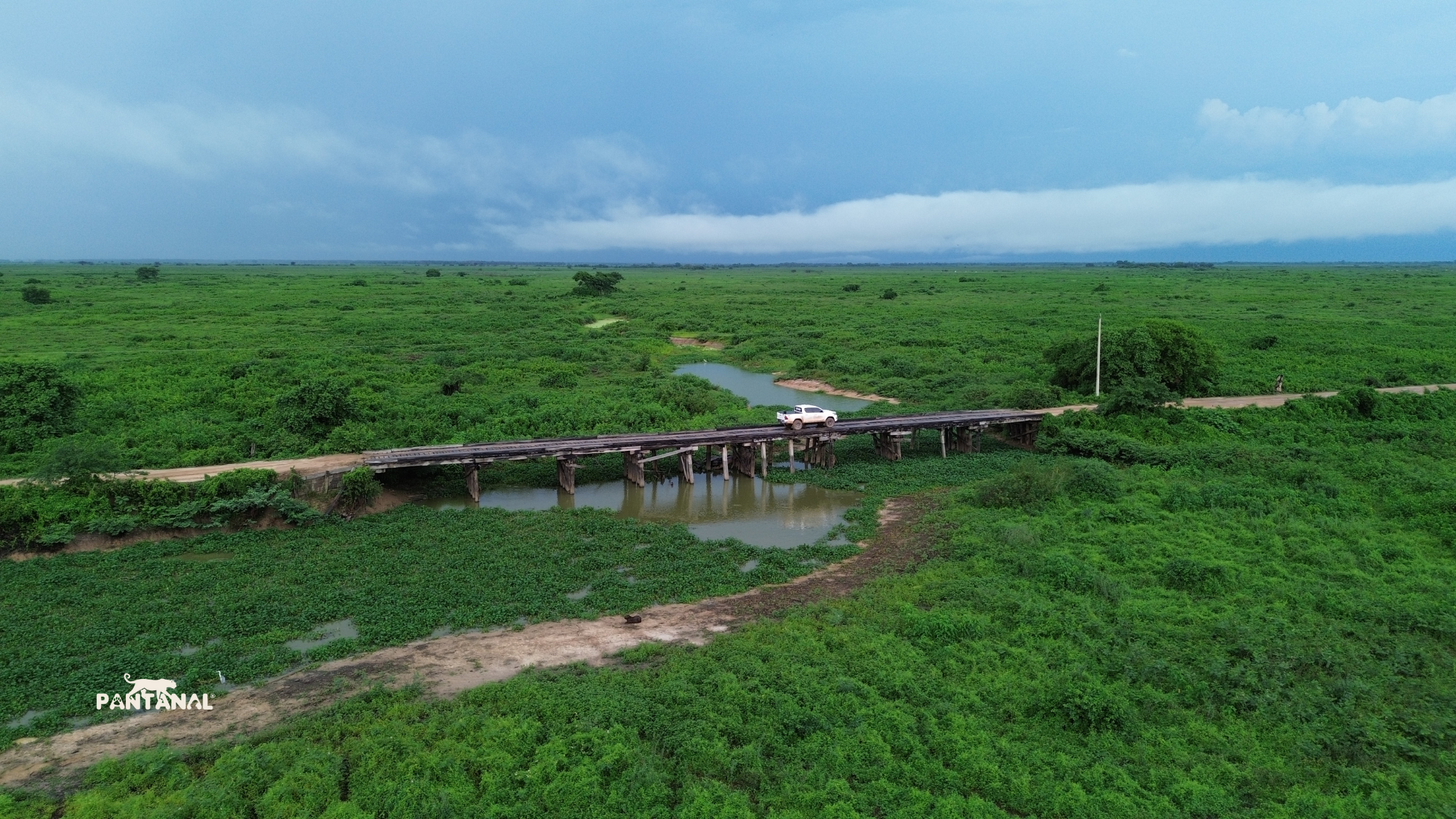Aerial view of a wooden bridge crossing the Pantanal wetlands with a vehicle on the Transpantaneira road