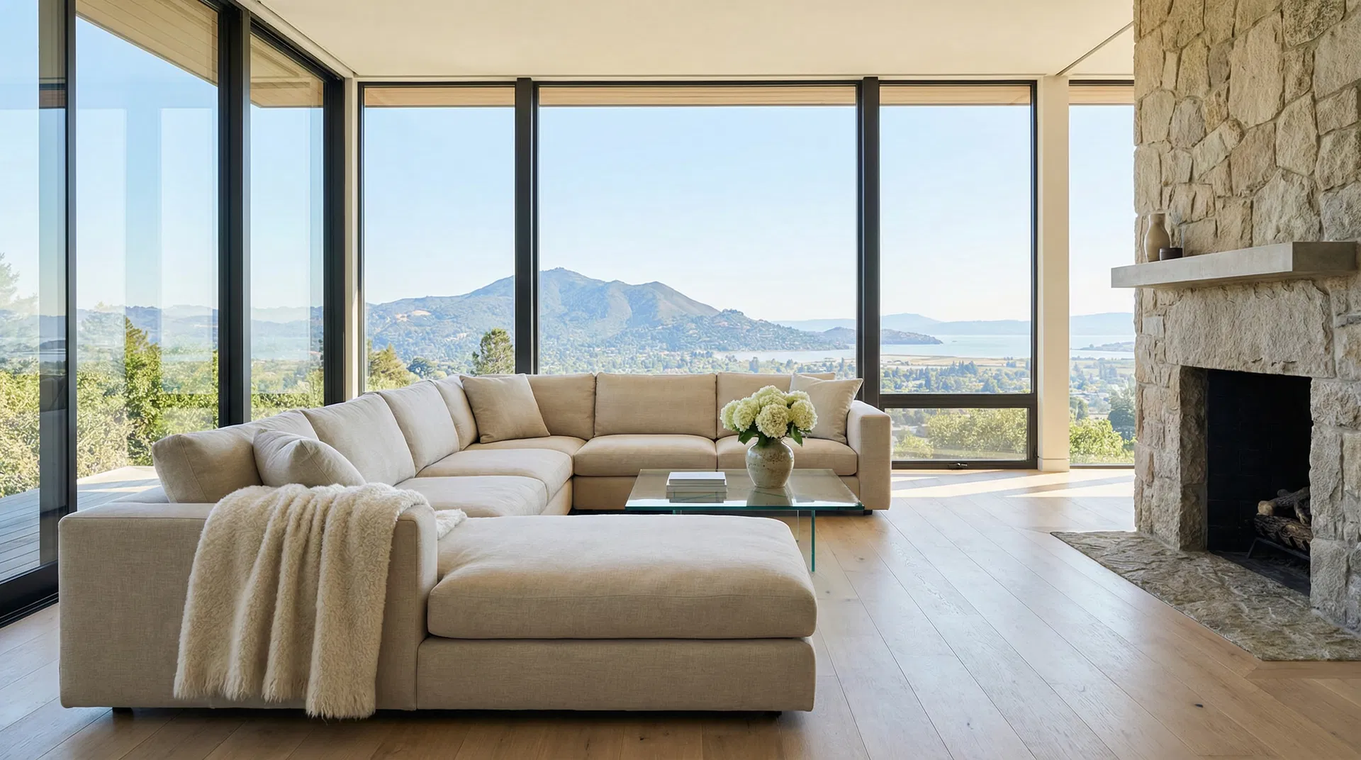 Grand Marin County estate living room with floor-to-ceiling windows overlooking Mount Tamalpais and San Francisco Bay, immaculately clean white oak floors and stone fireplace