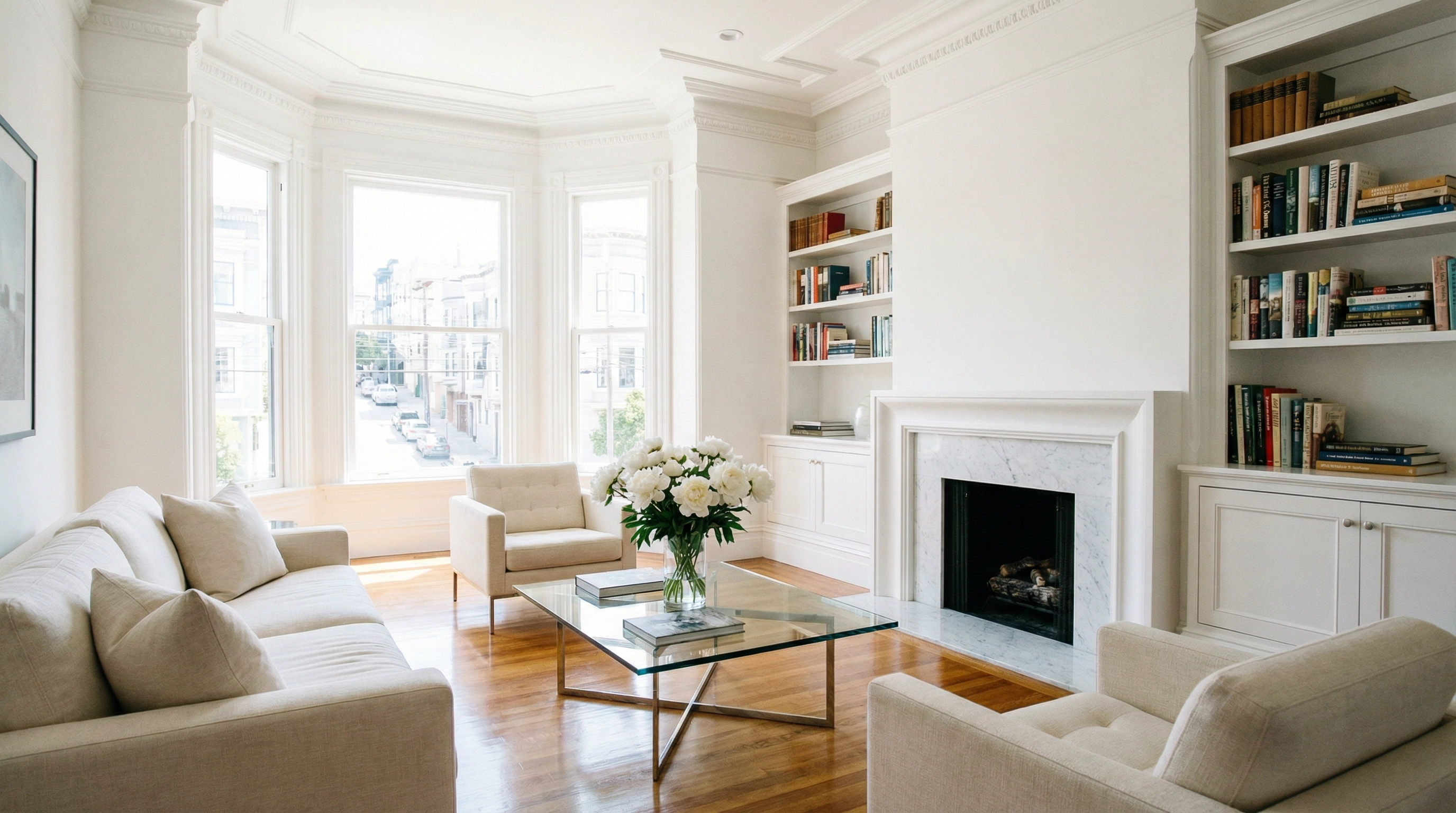 Spotlessly clean San Francisco Victorian living room with gleaming hardwood floors, white peonies, marble fireplace, and bay windows