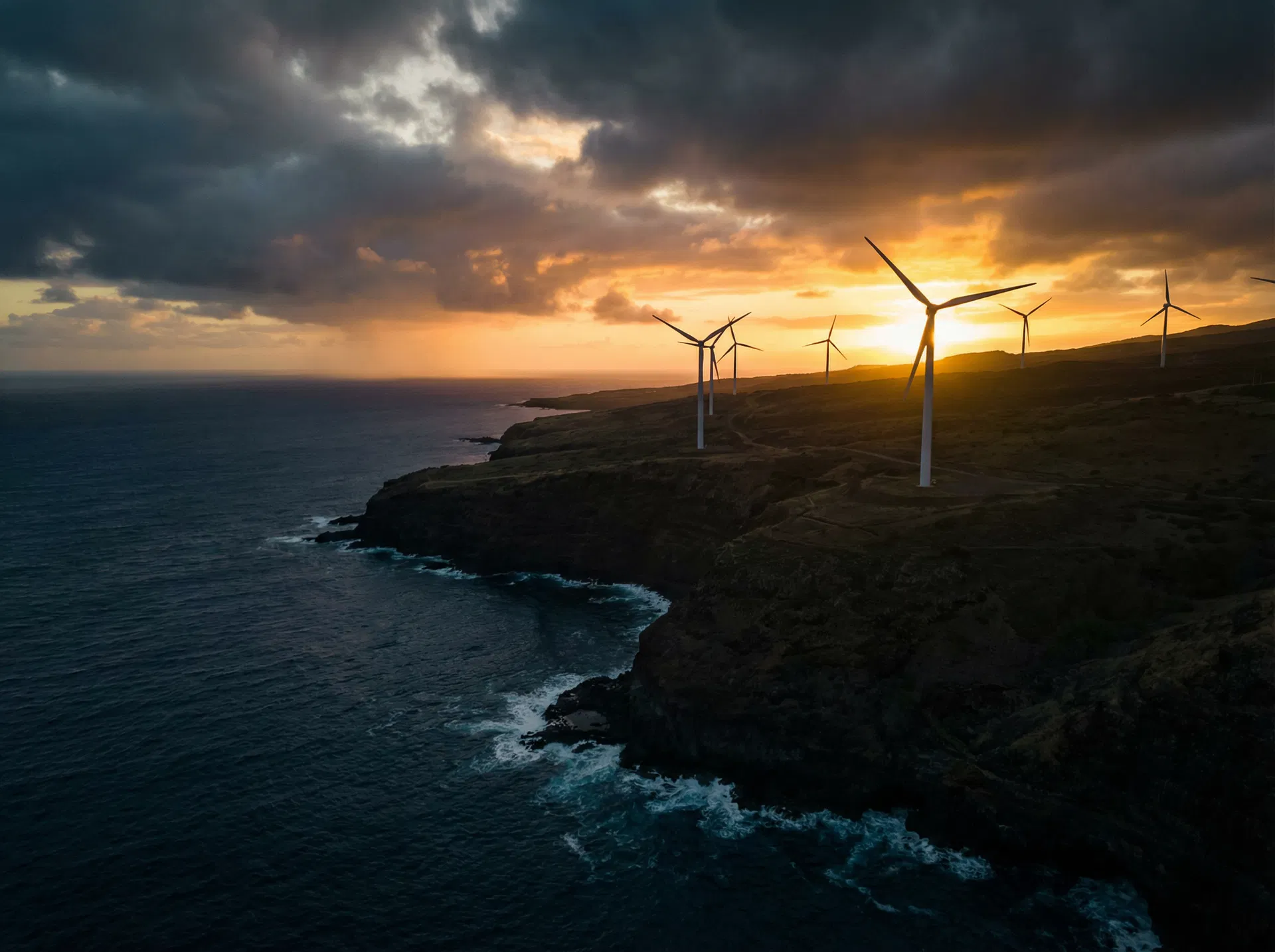 Wind turbines on coastal cliff at sunset — renewable energy and environmental grandeur