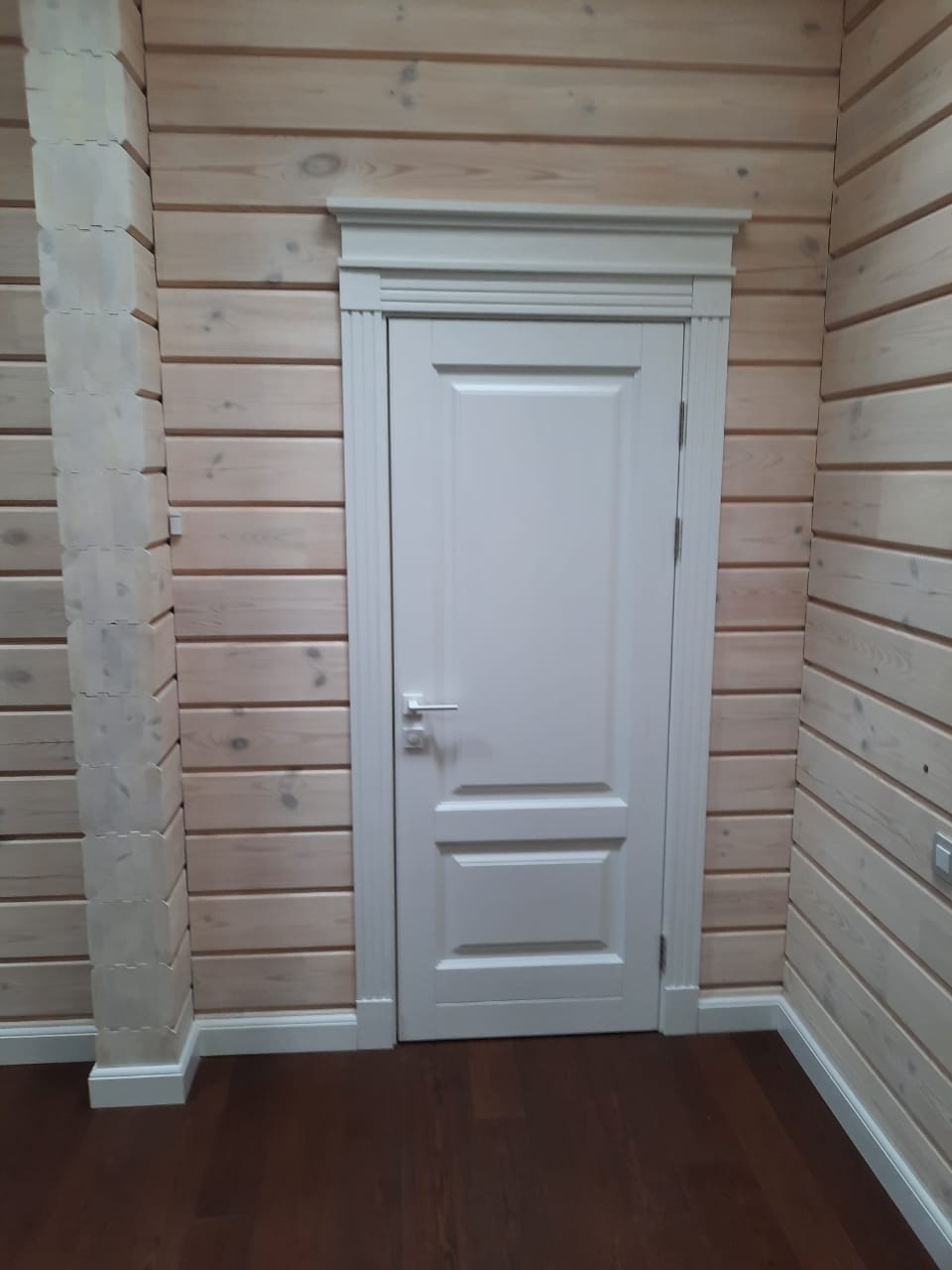 Белая дверь в деревянном интерьере