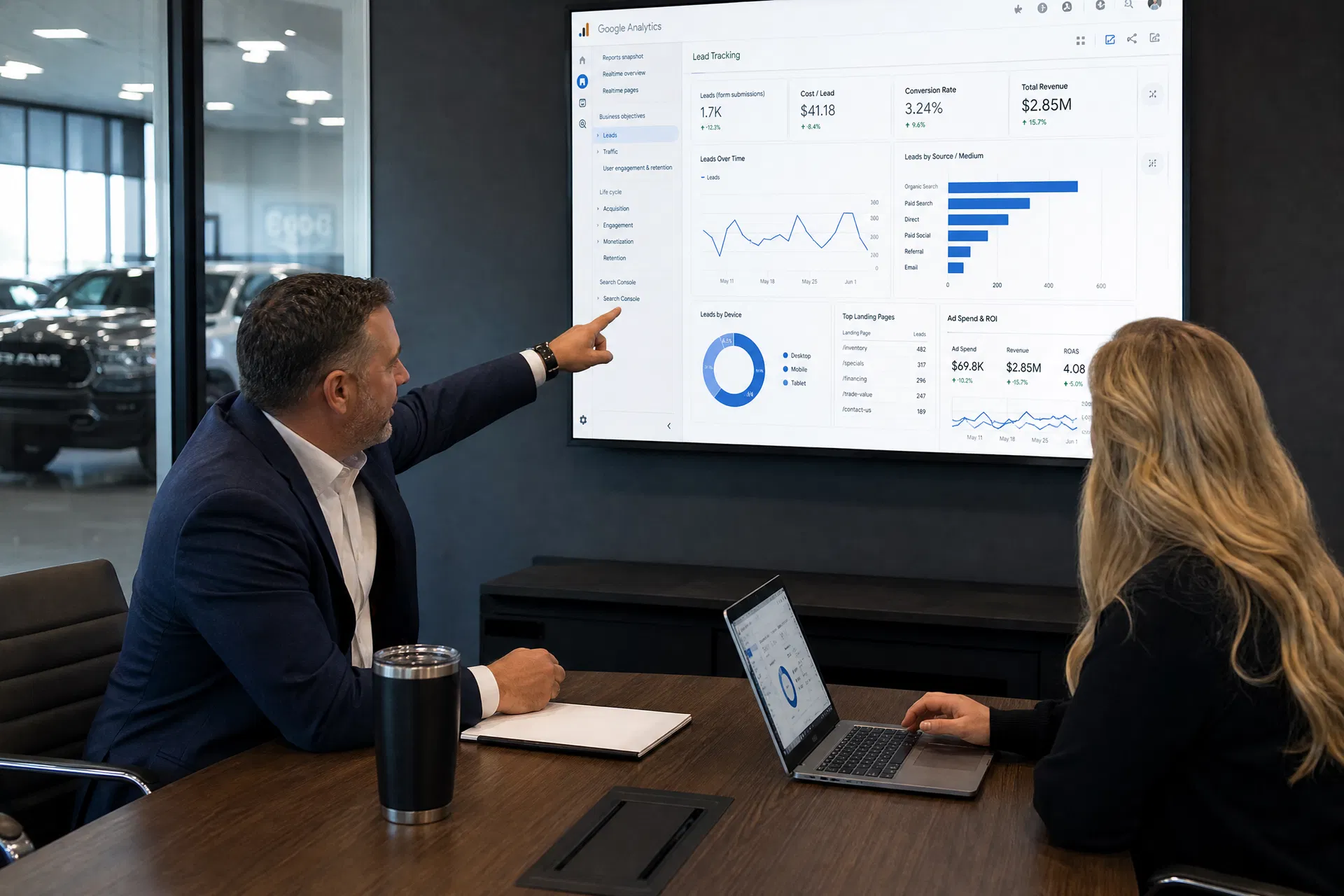 General manager and digital marketing specialist reviewing Google Analytics lead tracking and ad spend ROI in a dealership conference room