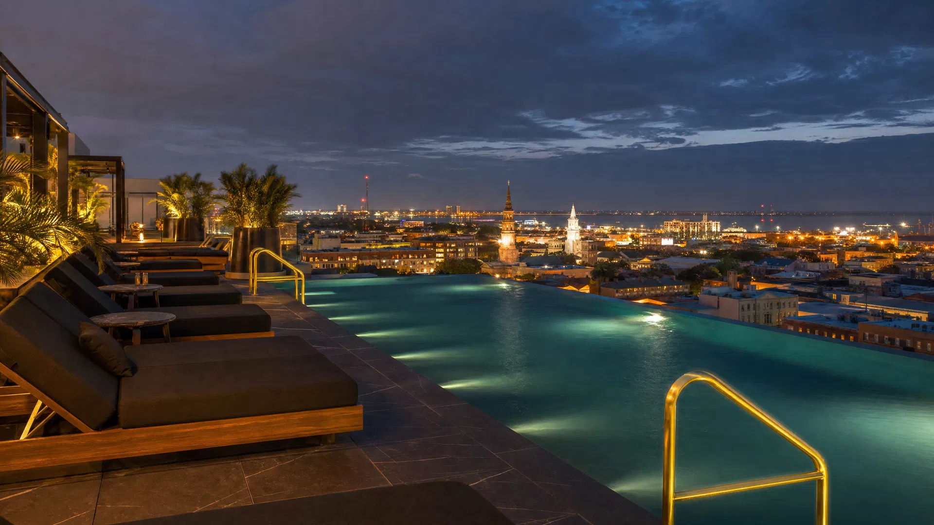 Wide-angle infinity pool at dusk with Charleston skyline