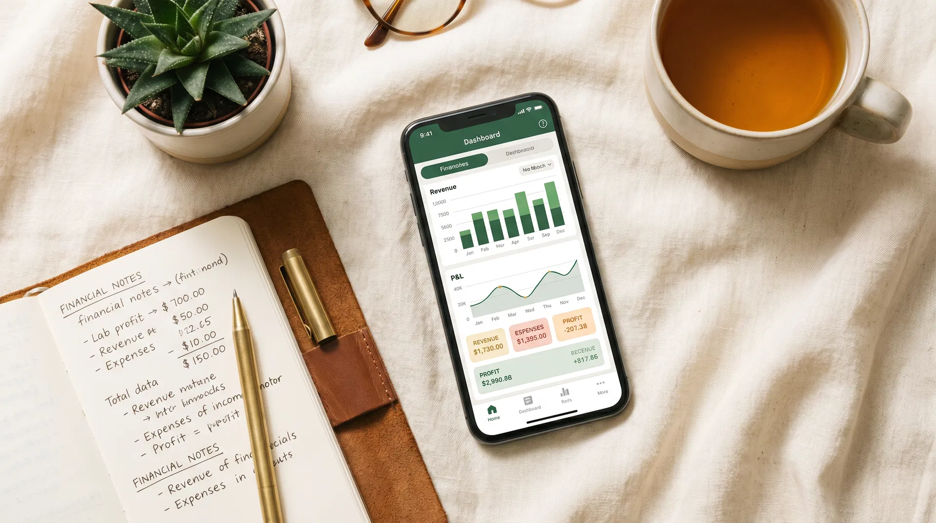 A smartphone displaying a financial dashboard alongside a notebook with financial notes, on a warm linen surface