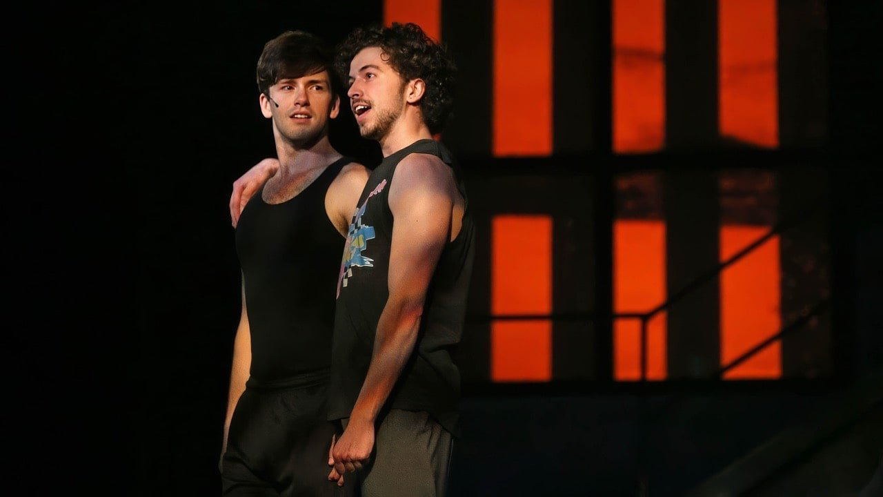 American Idiot - Scenic design by Brandon PT Davis. Gritty urban landscape with stark scaffolding, bold graffiti, and raw industrial textures, reflecting youthful angst and rebellion.