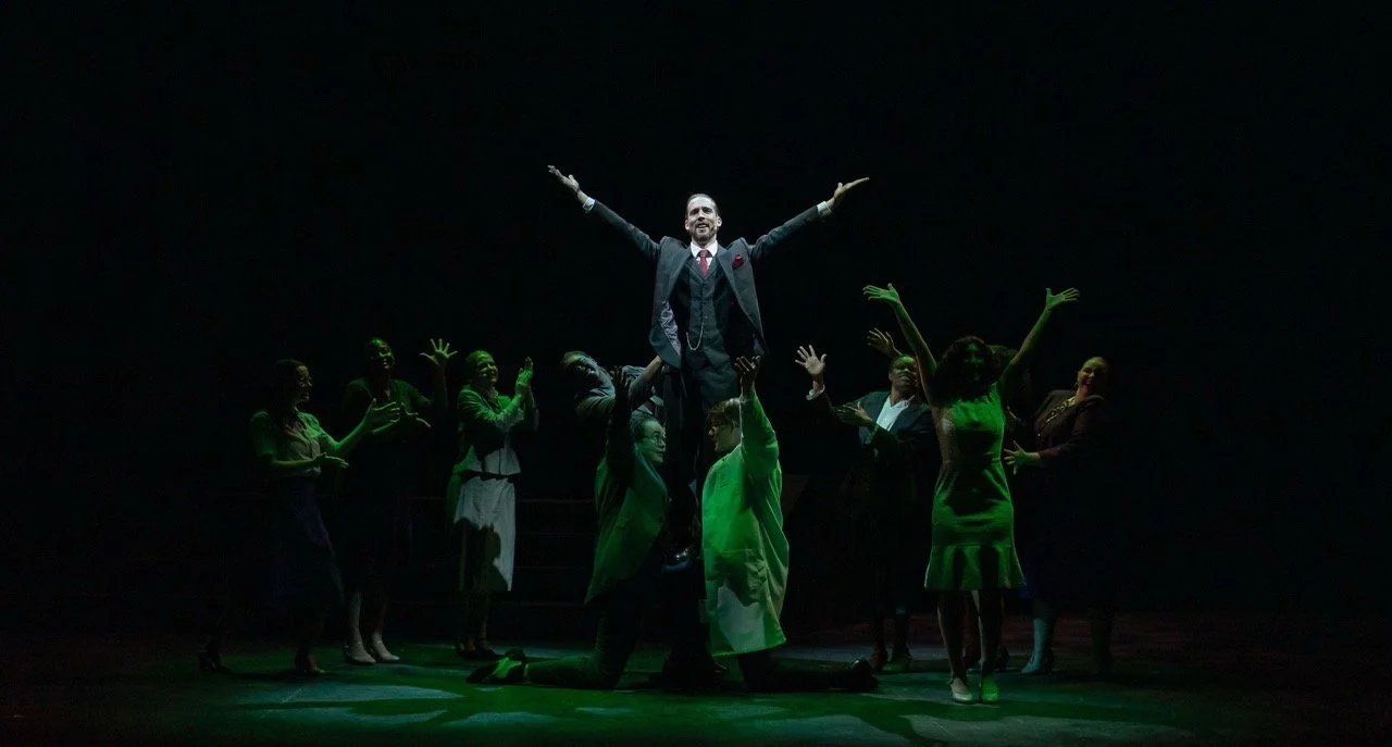 Urinetown - Scenic design by Brandon PT Davis. Gritty, industrial set with multi-level platforms, exposed pipes, and stark lighting, conveying a dystopian urban landscape.