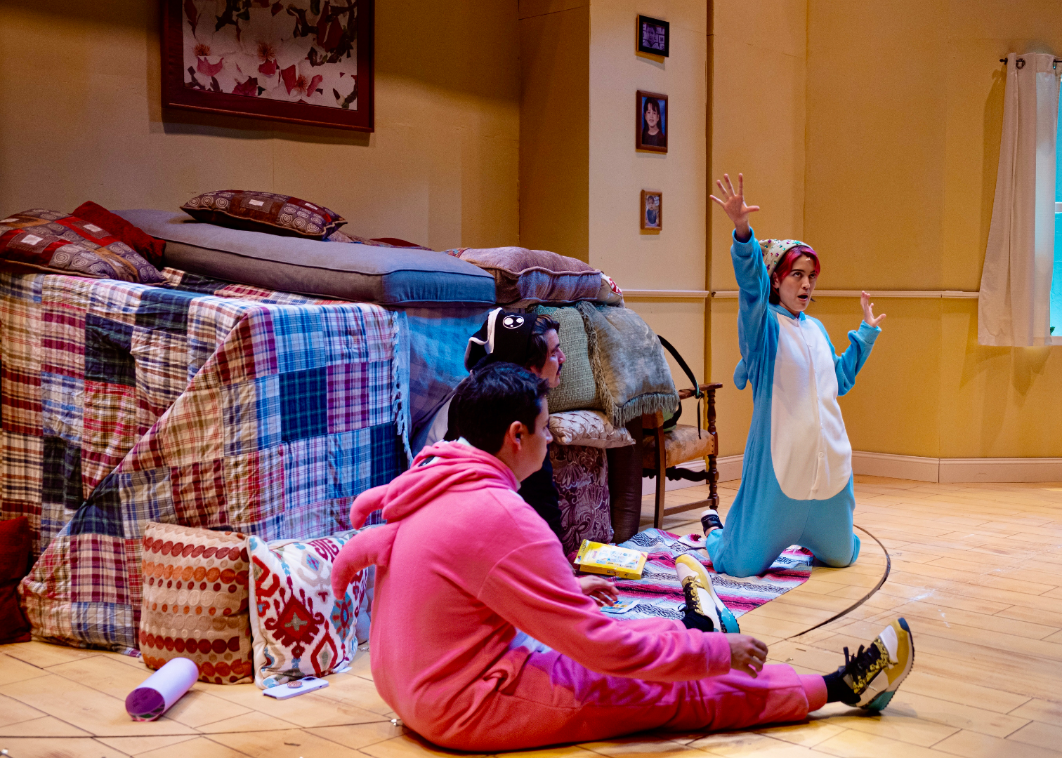 ¡LOTERIA: GAME ON! - Scenic design by Brandon PT Davis. A vibrant, game-themed suburban basement living room set.