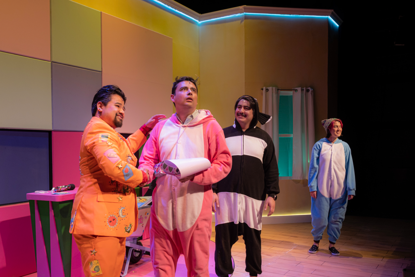 ¡LOTERIA: GAME ON! - Scenic design by Brandon PT Davis. A vibrant, game-themed suburban basement living room set.