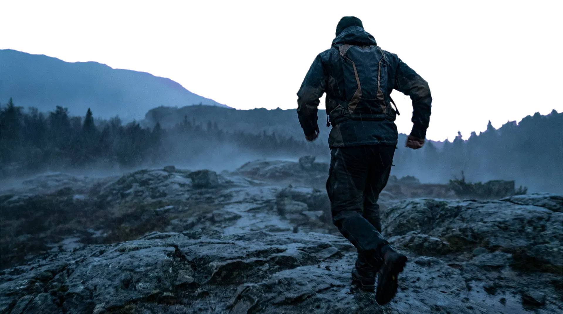 Anonymous figure moving through rugged terrain in low light