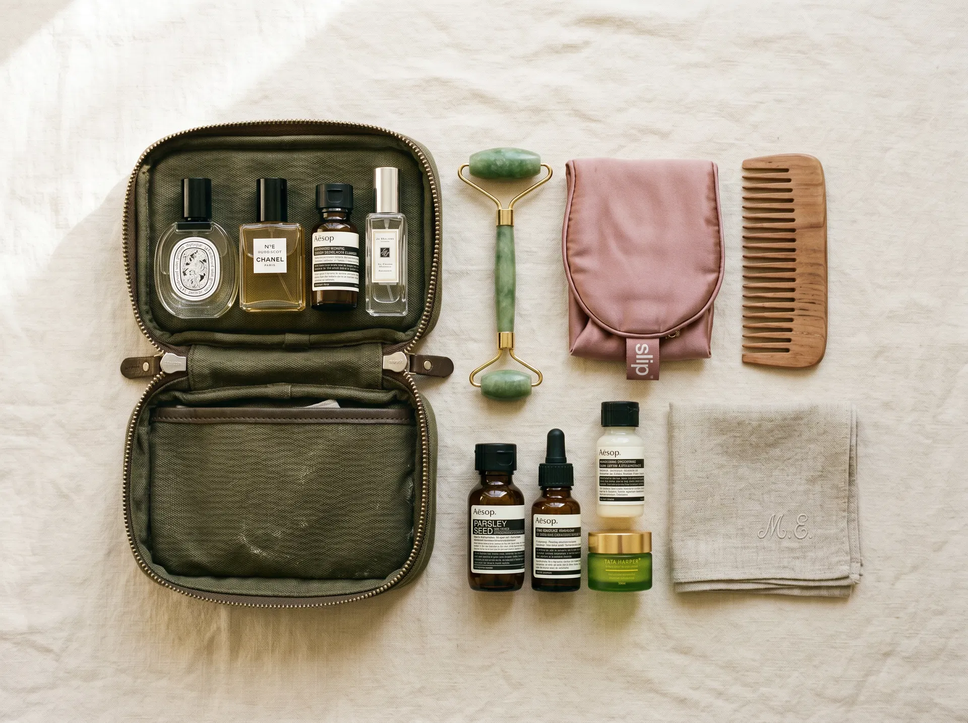 Organized travel toiletry kit laid flat with skincare, jade roller, silk eye mask, and dopp bag