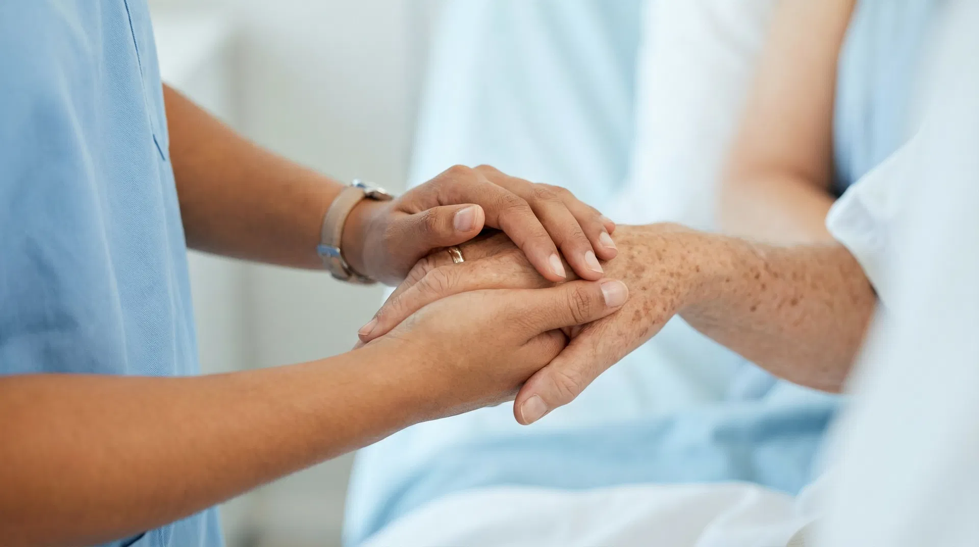 Caring professional holding a senior person's hand