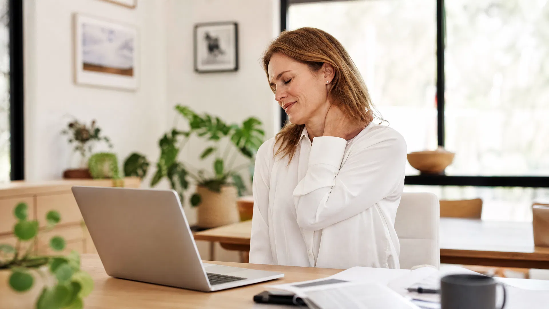 Woman at desk with neck pain, Australian home office setting
