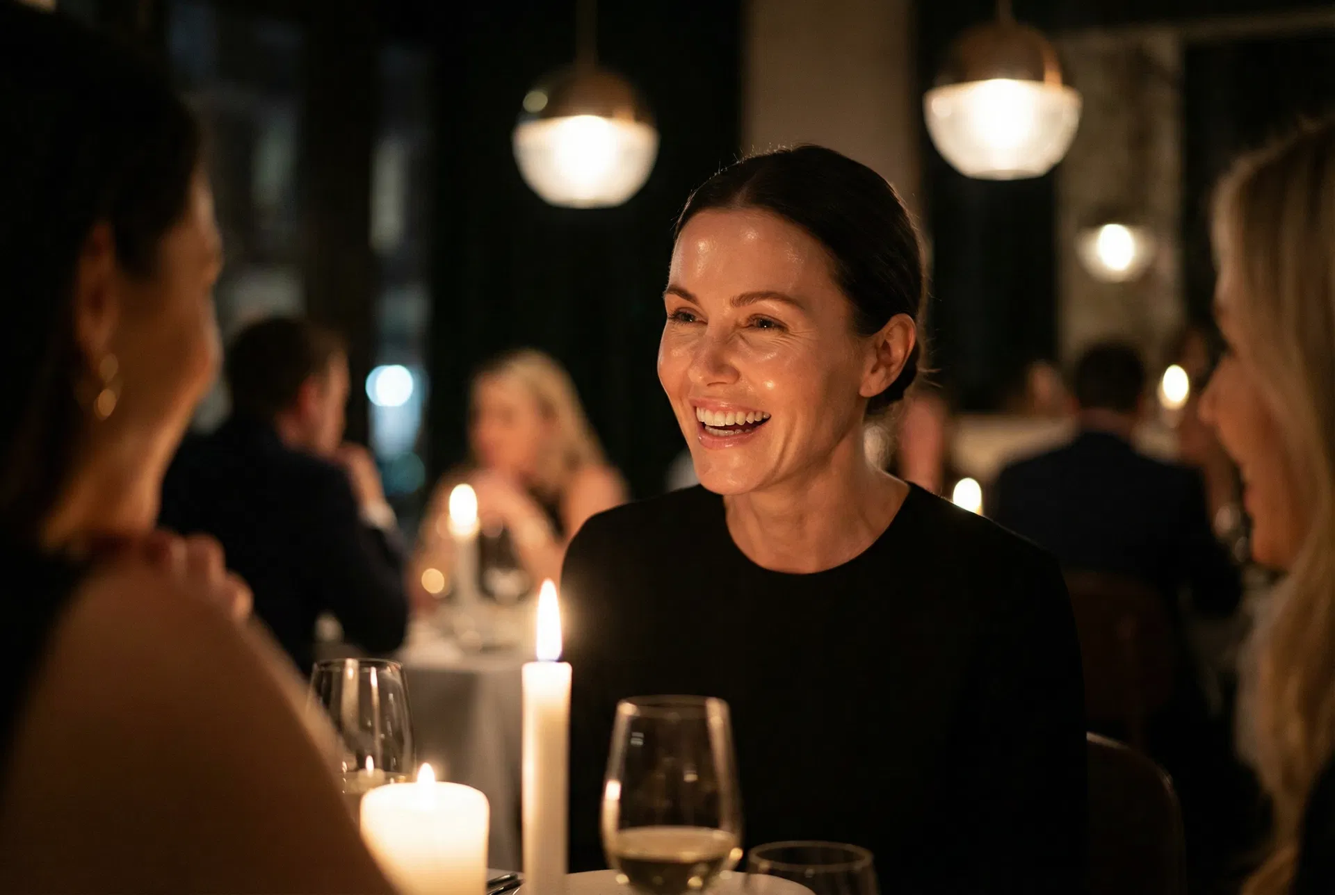 Confident woman laughing at an upscale dinner, radiant glowing skin