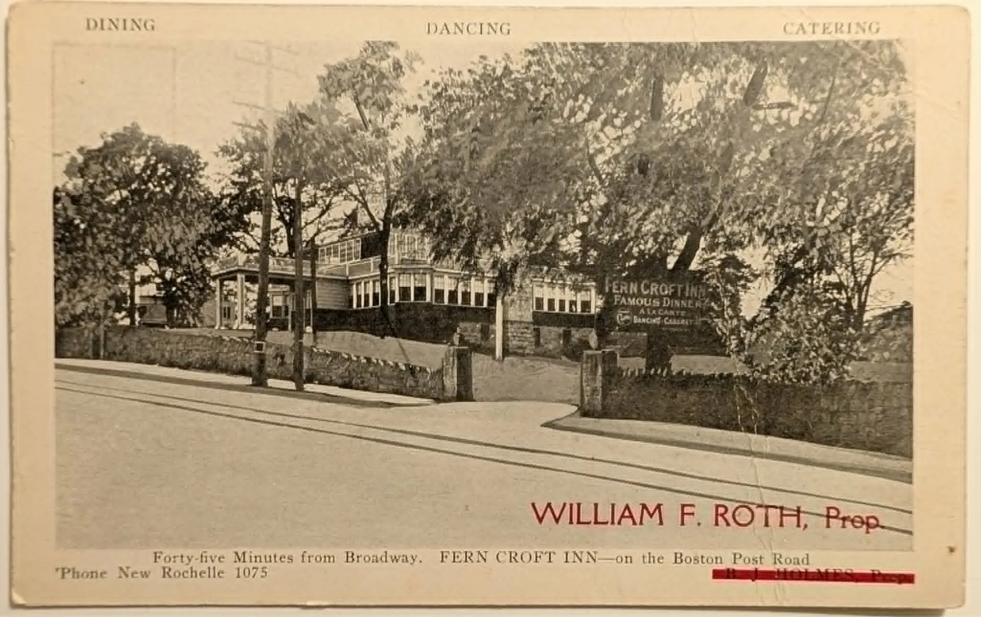 A horizontal vintage black-and-white postcard depicting the Fern Croft Inn, a multi-story building situated behind a stone retaining wall and surrounded by trees. A large sign on the building reads "FERN CROFT INN / FAMOUS DINNERS / A LA CARTE / DANCING CABARET". The top border features the words "DINING," "DANCING," "CATERING." At the bottom, the name "WILLIAM F. ROTH, Prop." is printed in striking red ink directly over a crossed-out previous name (B. J. Holmes). Below this, printed text reads "Forty-five Minutes from Broadway. FERN CROFT INN—on the Boston Post Road" and "'Phone New Rochelle 1075". The reverse shows a divided back with ornate Gothic lettering reading "Post Card".