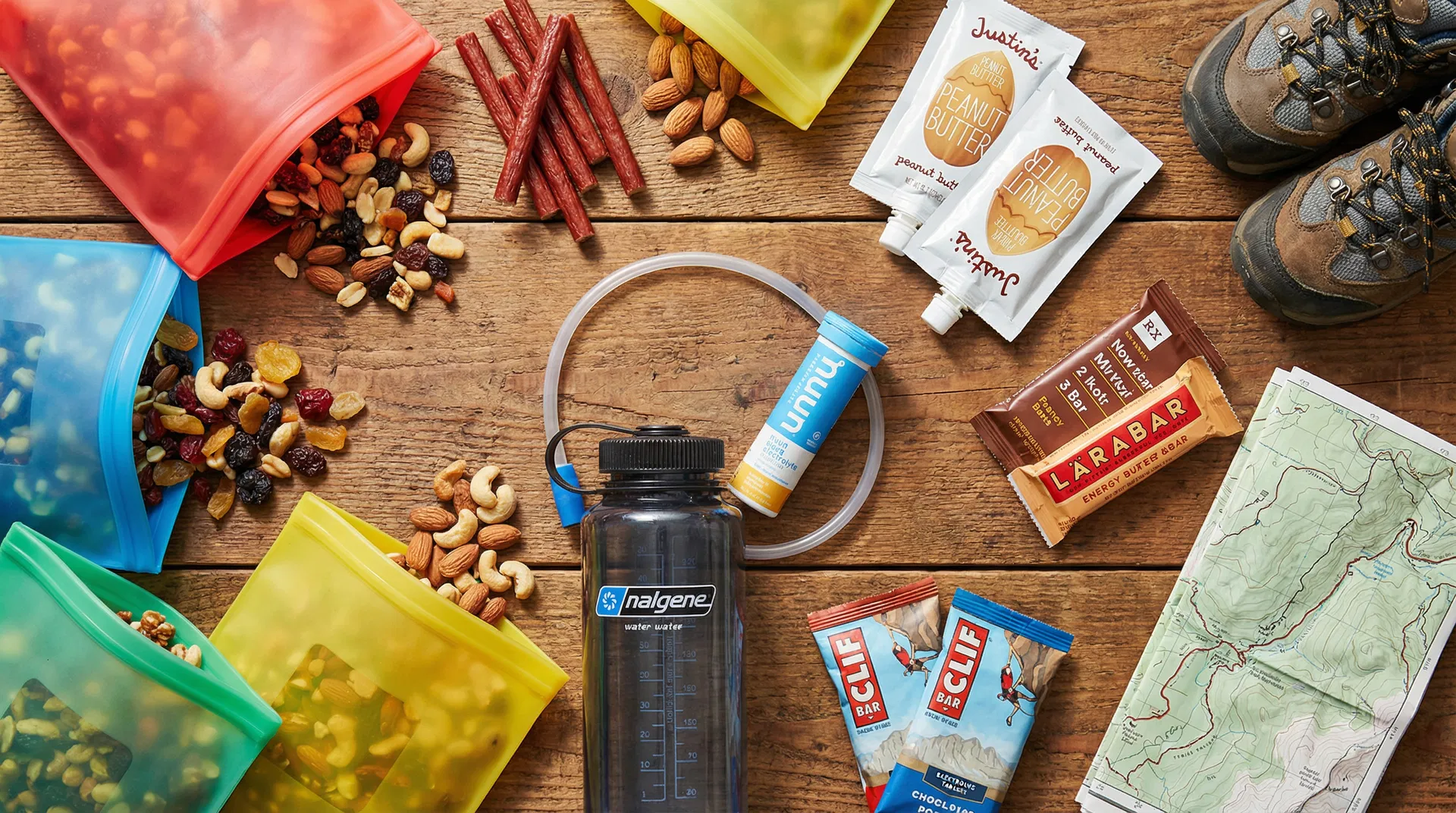 Flat-lay of trail snacks including nuts, meat sticks, and electrolyte tabs on a trail map
