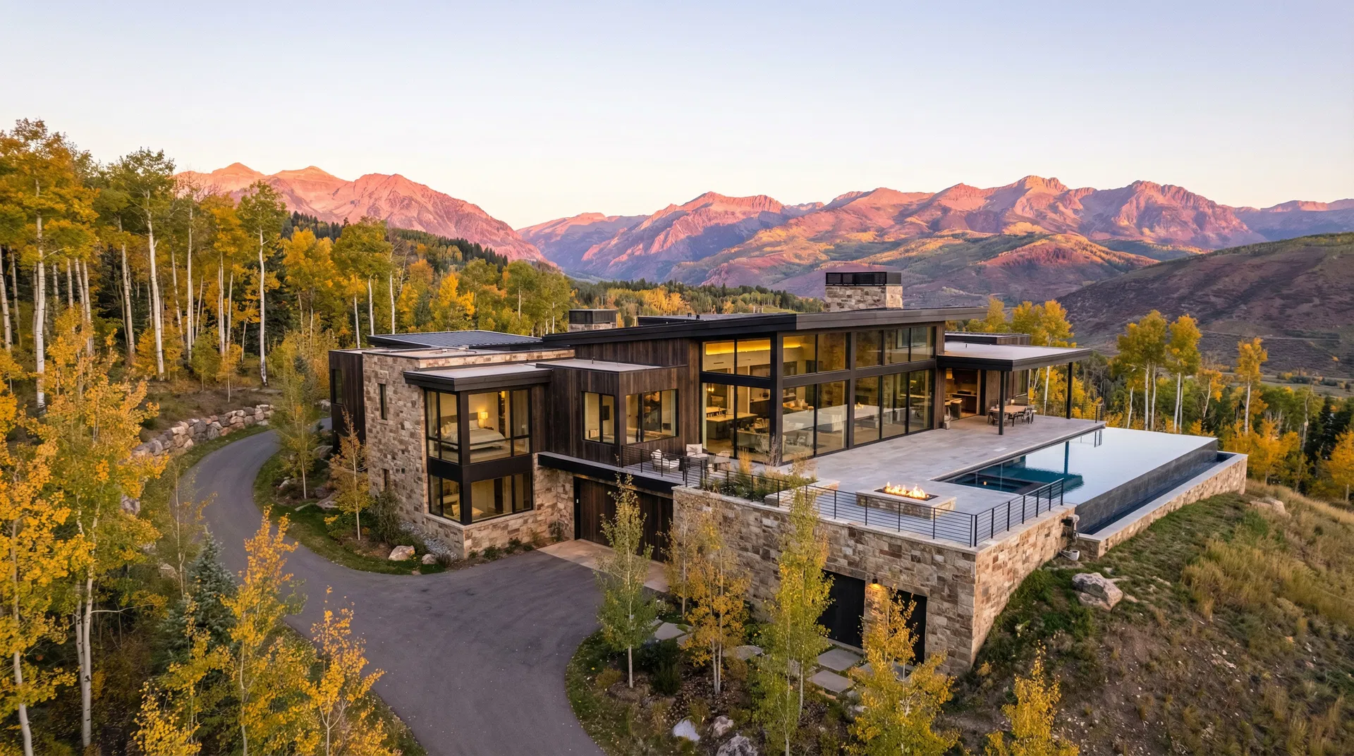 Aerial view of a completed luxury mountain home nestled into fall aspens at sunrise