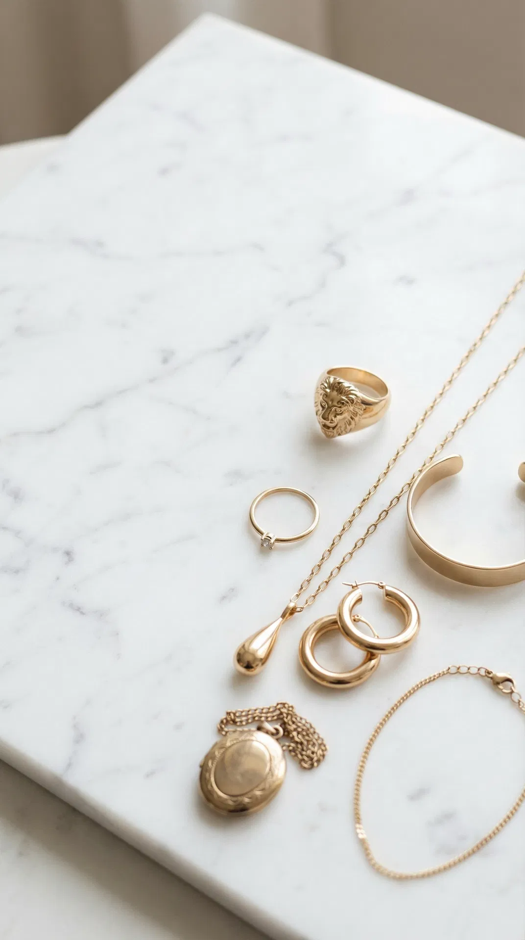 Scattered gold jewellery pieces on white marble — Auric Studio