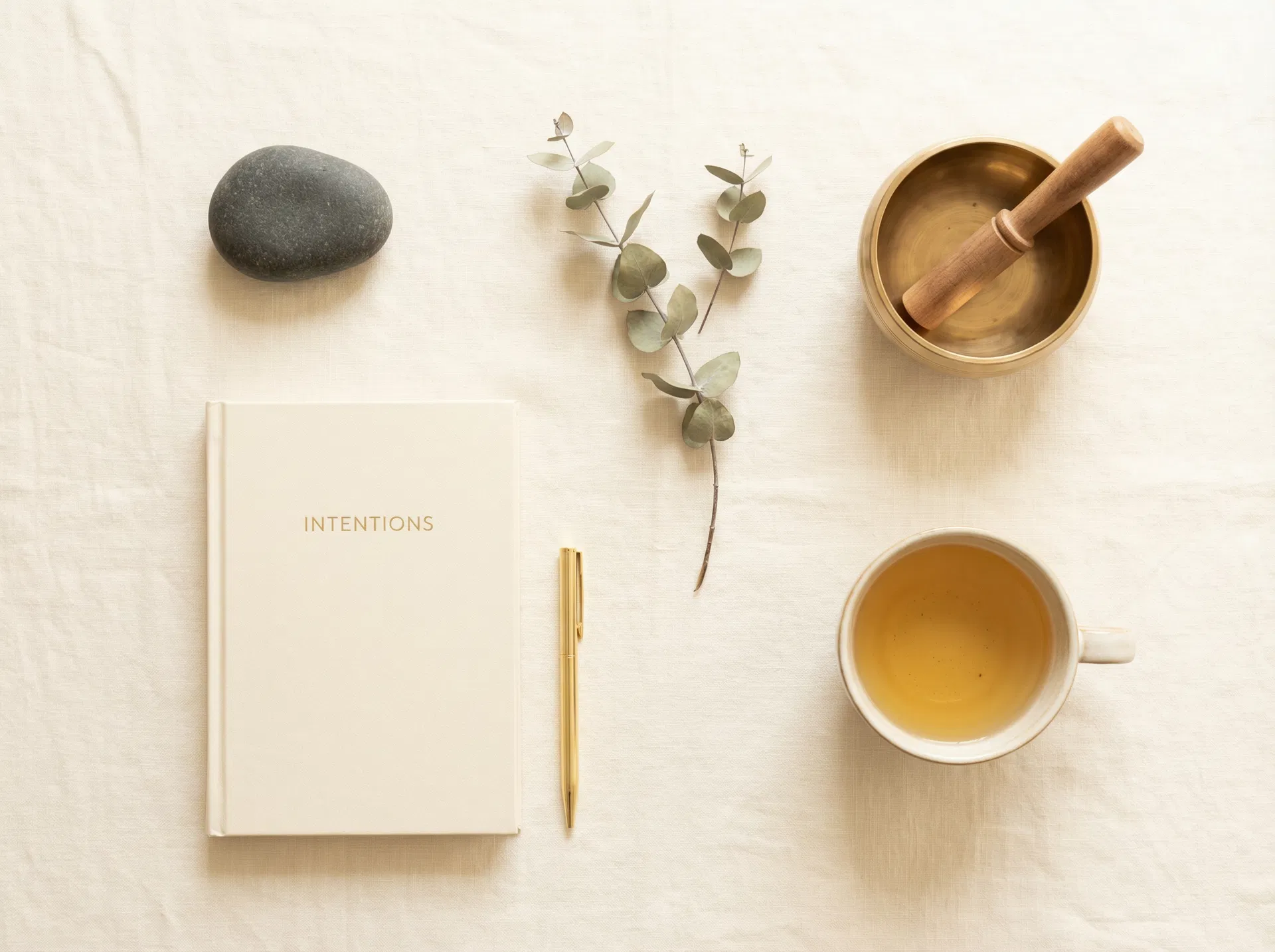 Wellness ritual flat-lay with journal, singing bowl, and golden tea