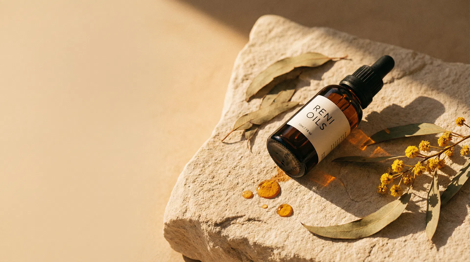 Reni Oils amber dropper bottle on sandstone with eucalyptus