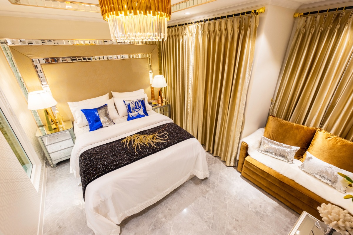 Studio Condo for Sale at Seven Seas Le Carnival: Overhead view of the bed with gold headboard, sofa, and gold curtains.