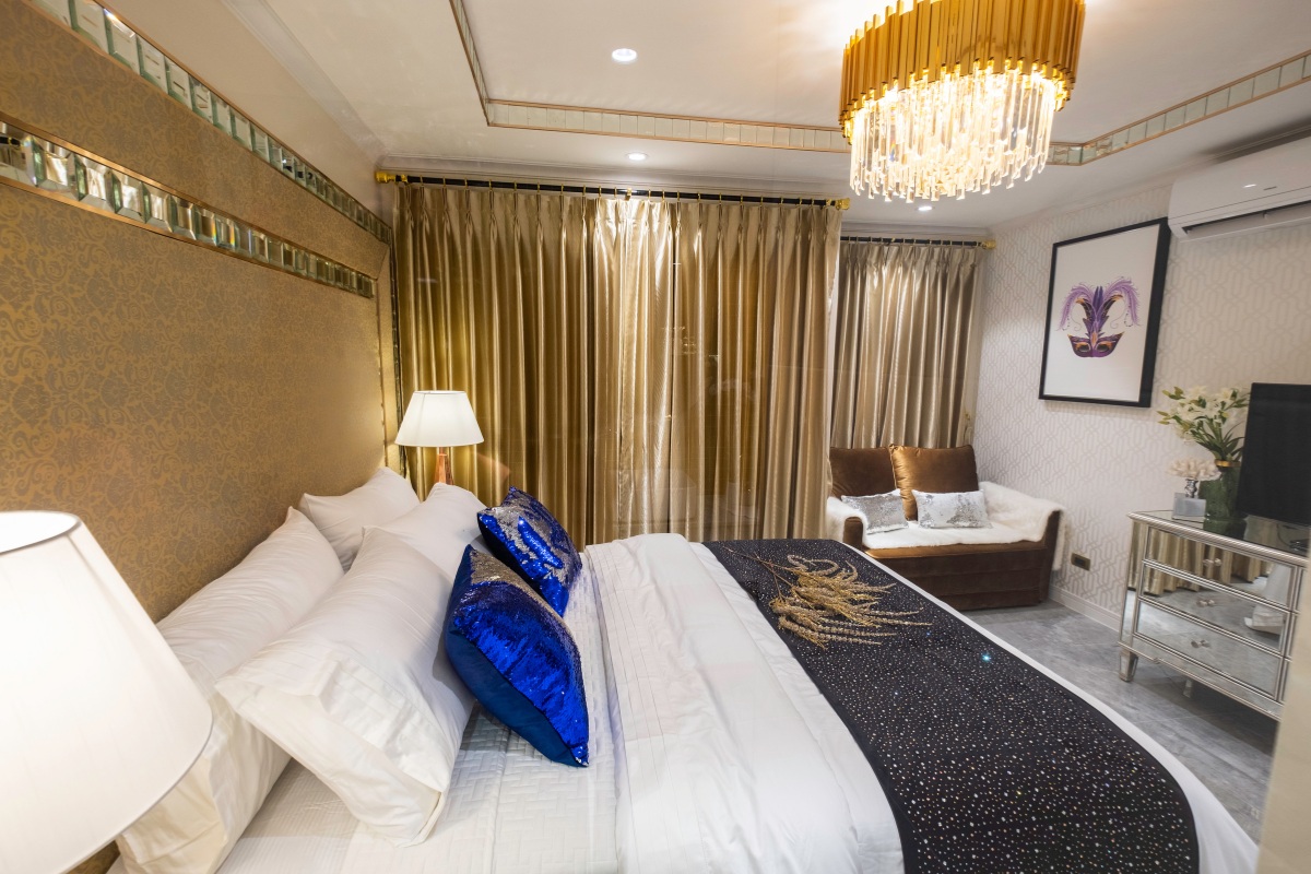 Studio Condo for Sale at Seven Seas Le Carnival: Bedroom with large bed, golden headboard, and elegant gold curtains.